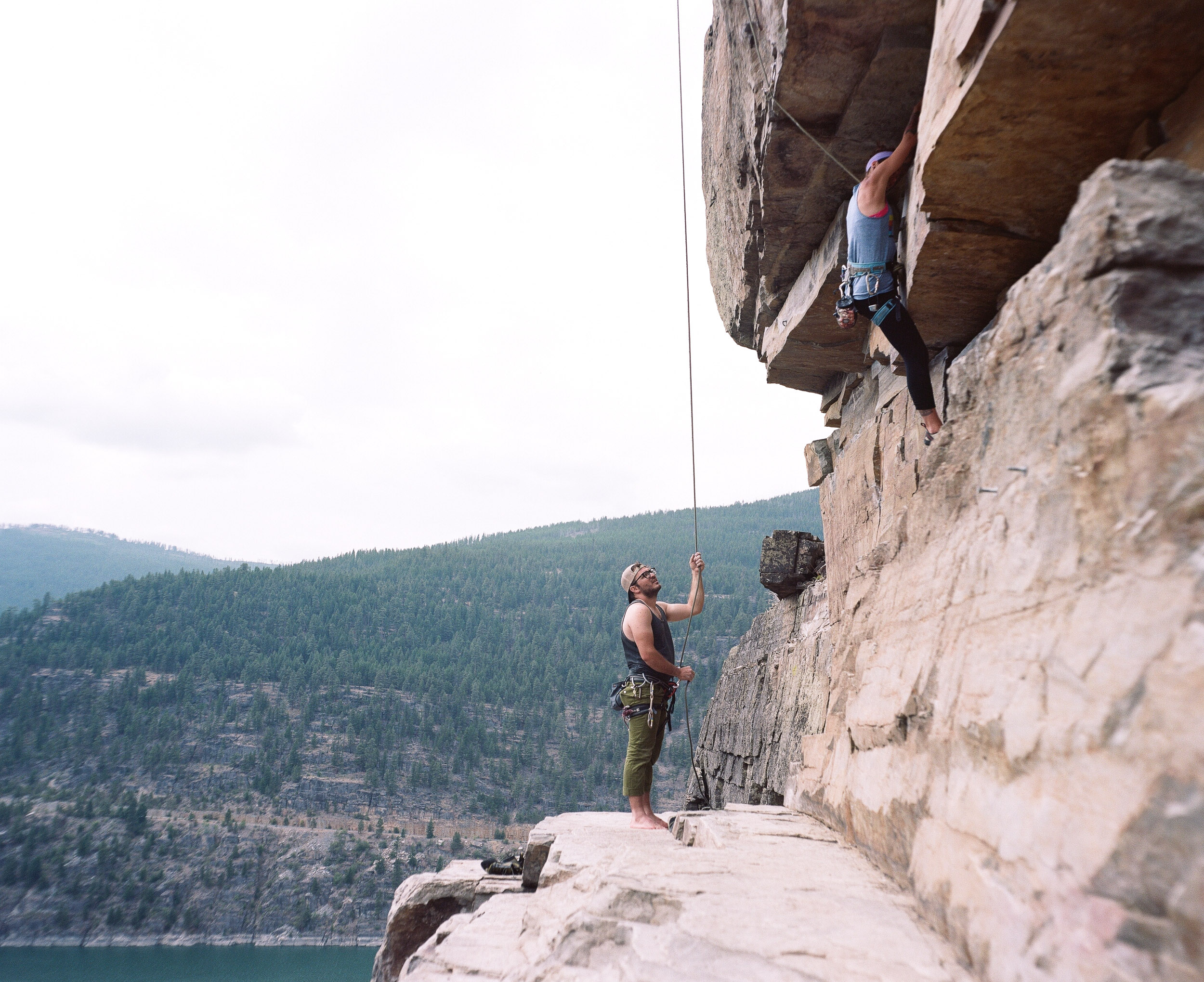 Rock climbers on a ledge over lake Koocanusa