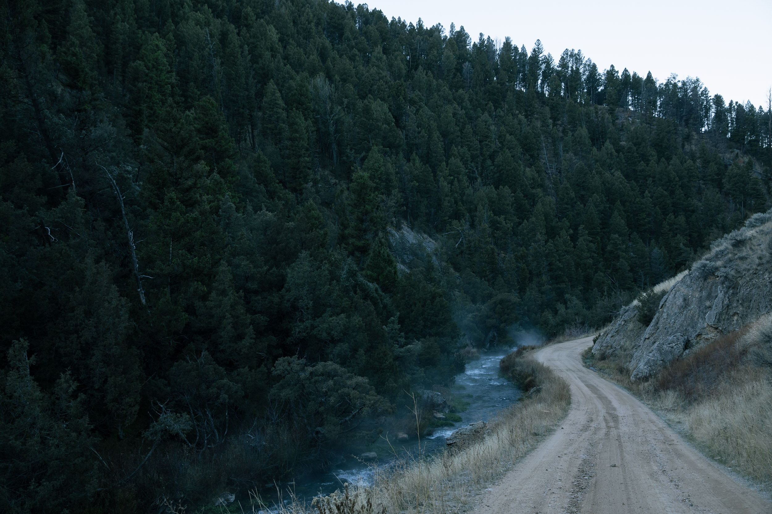 Dirtroad along a river in the mountains with mist