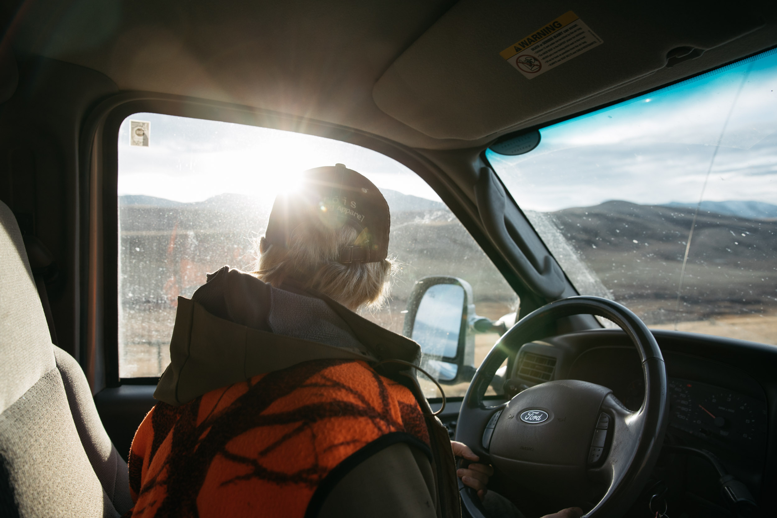 Hunter with blaze orange vest looking out of truck window