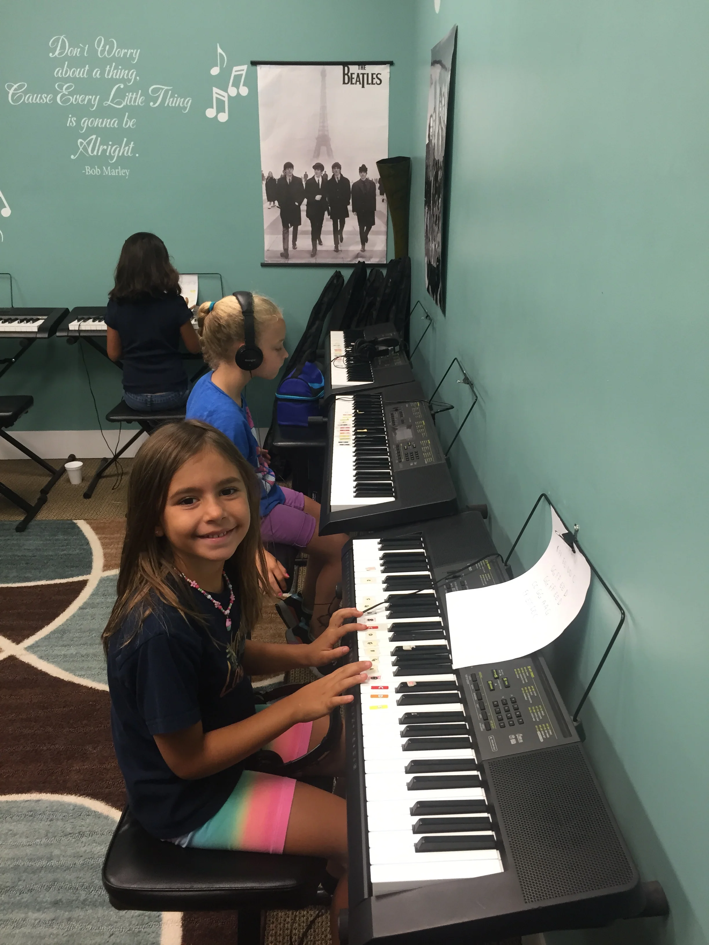 LEAH practices her new hand position while playing her piece in group piano class, WHILE MADISON IS PREPARING TO PLAY A PIECE COMPLETELY MEMORIZED.