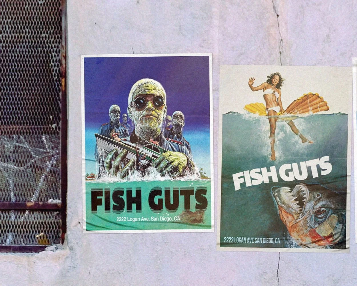 Two posters for 'Fish Guts' in San Diego, CA. The left poster features a cartoonish, sci-fi style image of a large yellow alien holding a spaceship, with three other alien figures behind it, and the address 2222 Logan Ave. The right poster shows a woman in a swimsuit standing on a large fish with a big open mouth, above water with a shell behind her, and the same address at the bottom.
