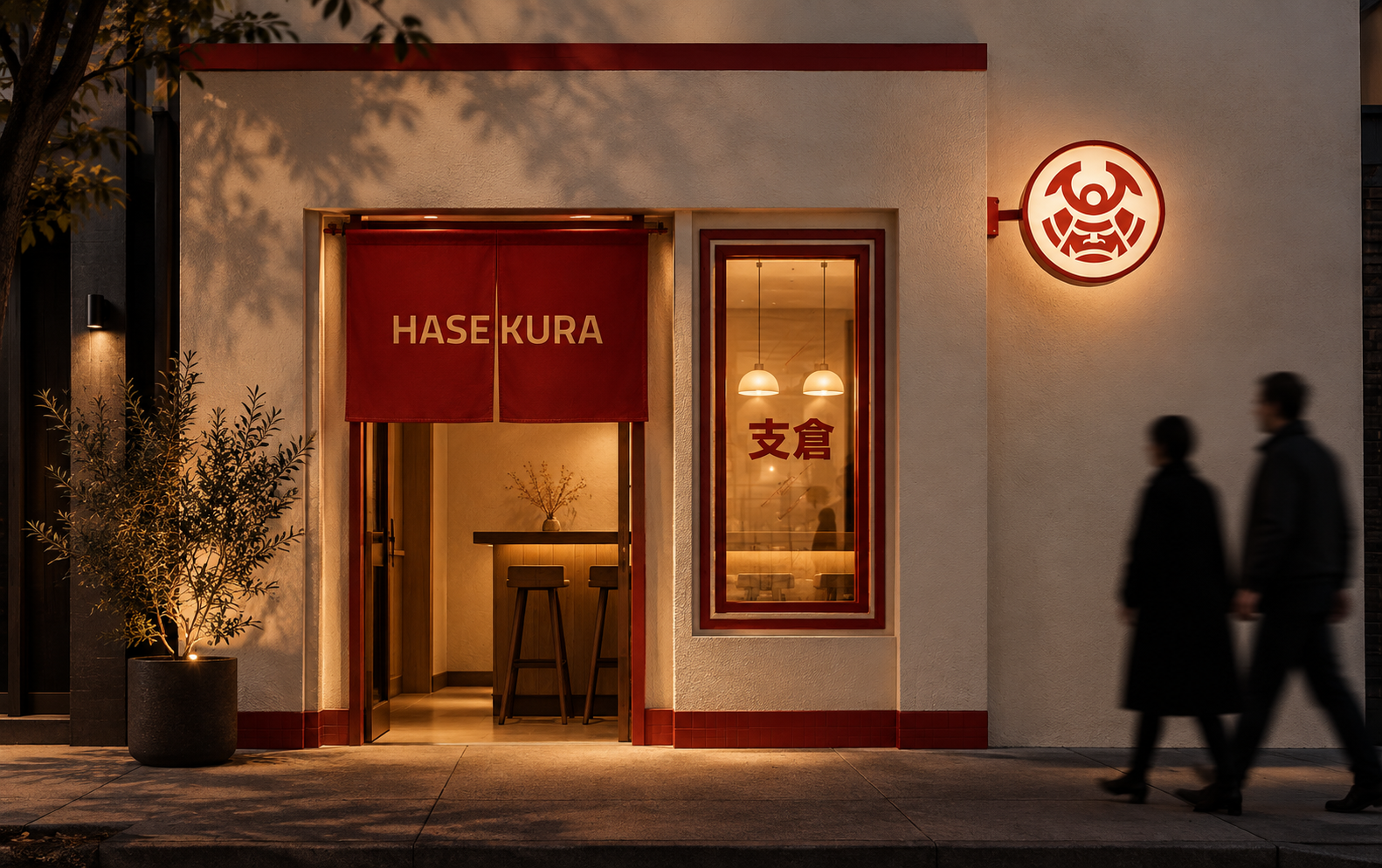 Exterior of a Japanese restaurant named Hasekura with a red noren curtain and illuminated signage, two people walking past at night.