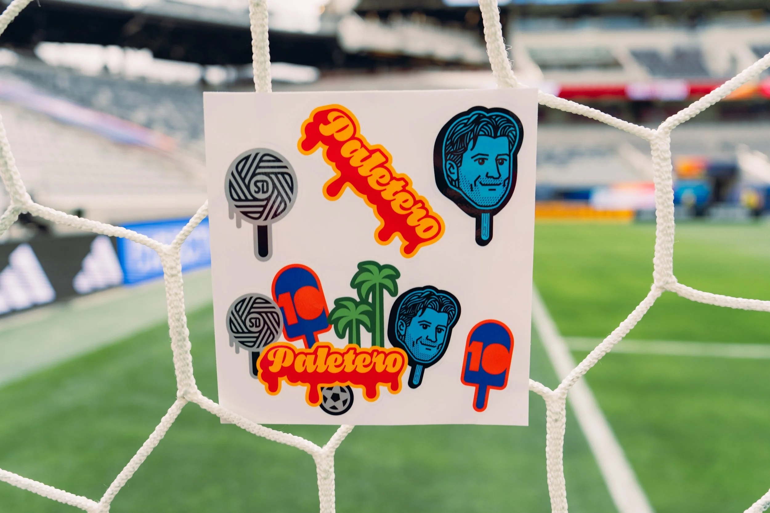Stickers on a soccer net featuring cartoon faces, sports-related images, and text related to the game.