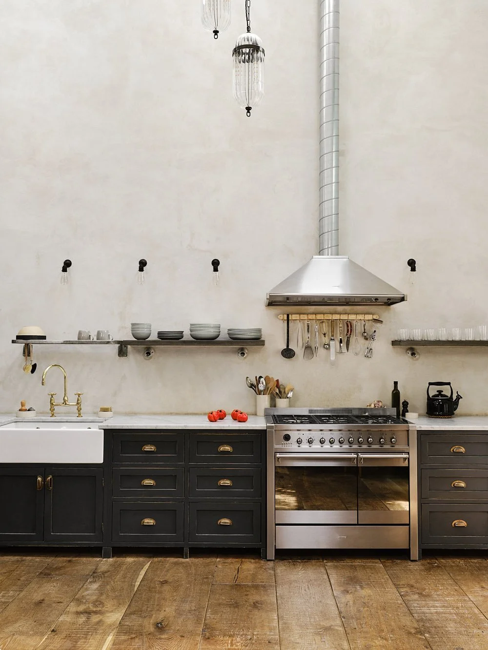 Wide kitchen view of the sand-cast bronze utensil rack, showing its full length and raw unlacquered finish in use.