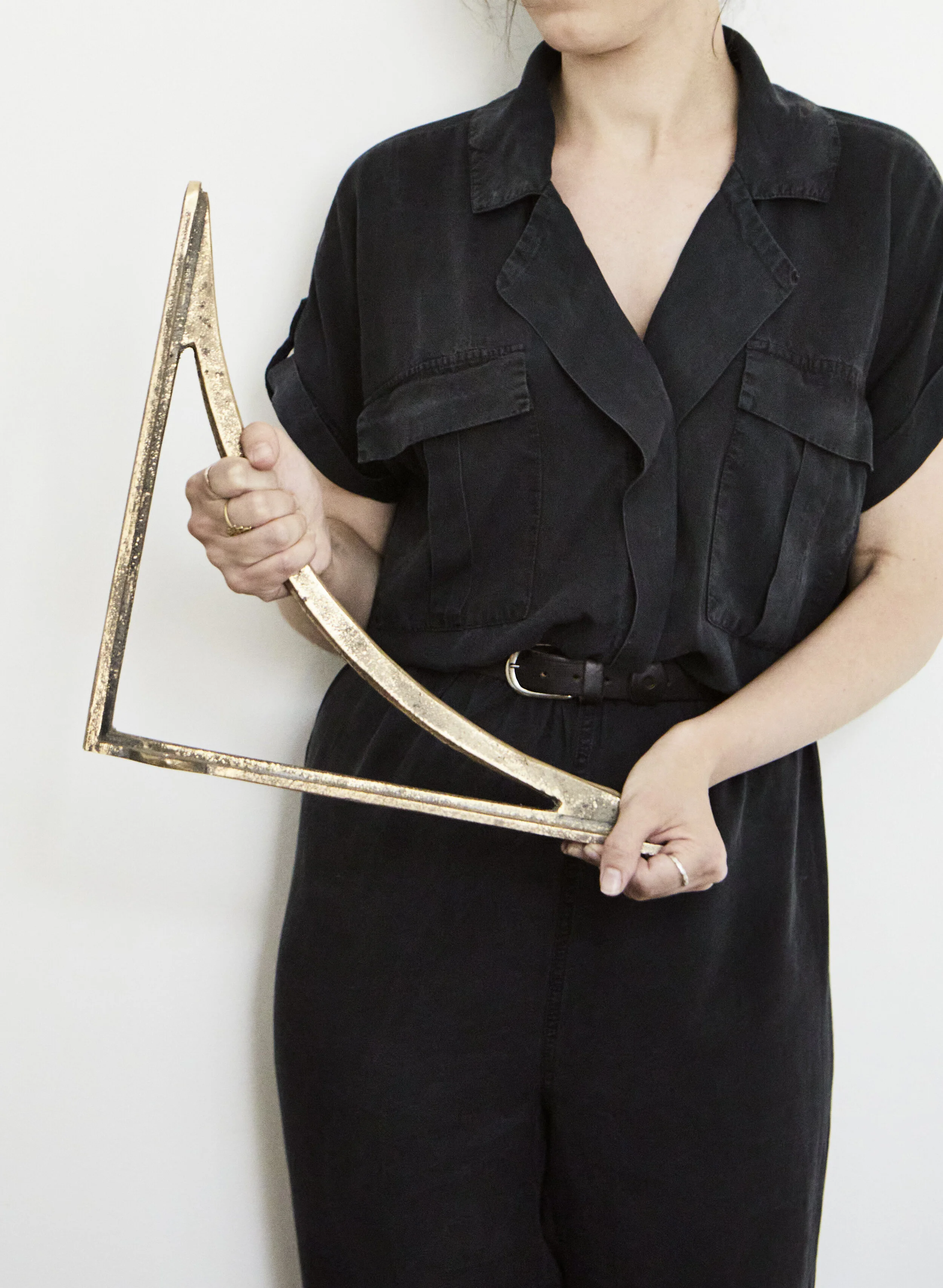 Cast Bronze Sink Brackets – Small, Medium & Large. An attractive woman in a black romper suit holds up the small bracket to show scale, highlighting its substantial size and weight.