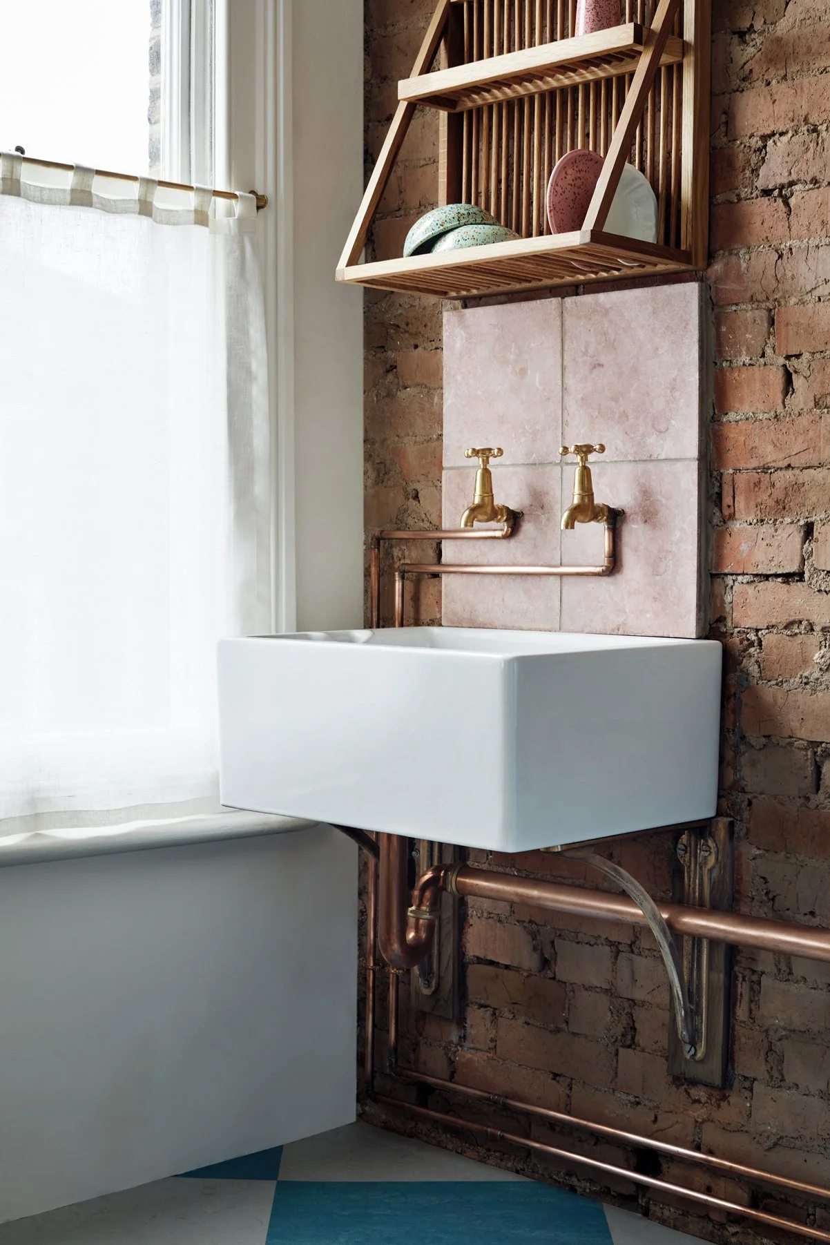 Cast Bronze Sink Brackets – Small, Medium & Large in an industrial kitchen, side view. Belfast sink by a window, supported by a small bracket, with a timber draining rack above the sink.
