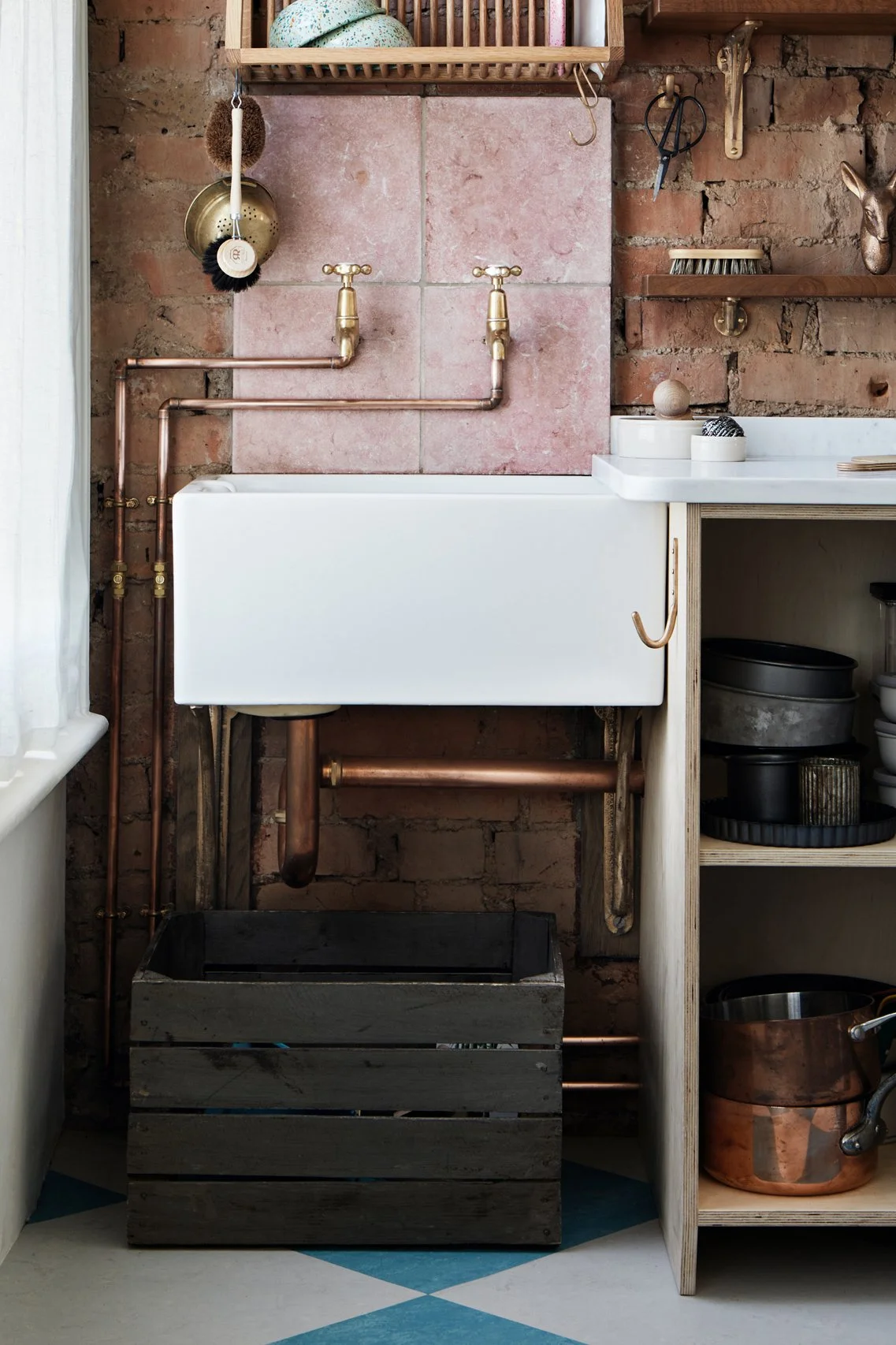 Alt text: Cast Bronze Sink Brackets – Small, Medium & Large supporting a Belfast sink in an industrial kitchen, shot front on. The small bracket is fixed to a brick wall, providing sturdy support.