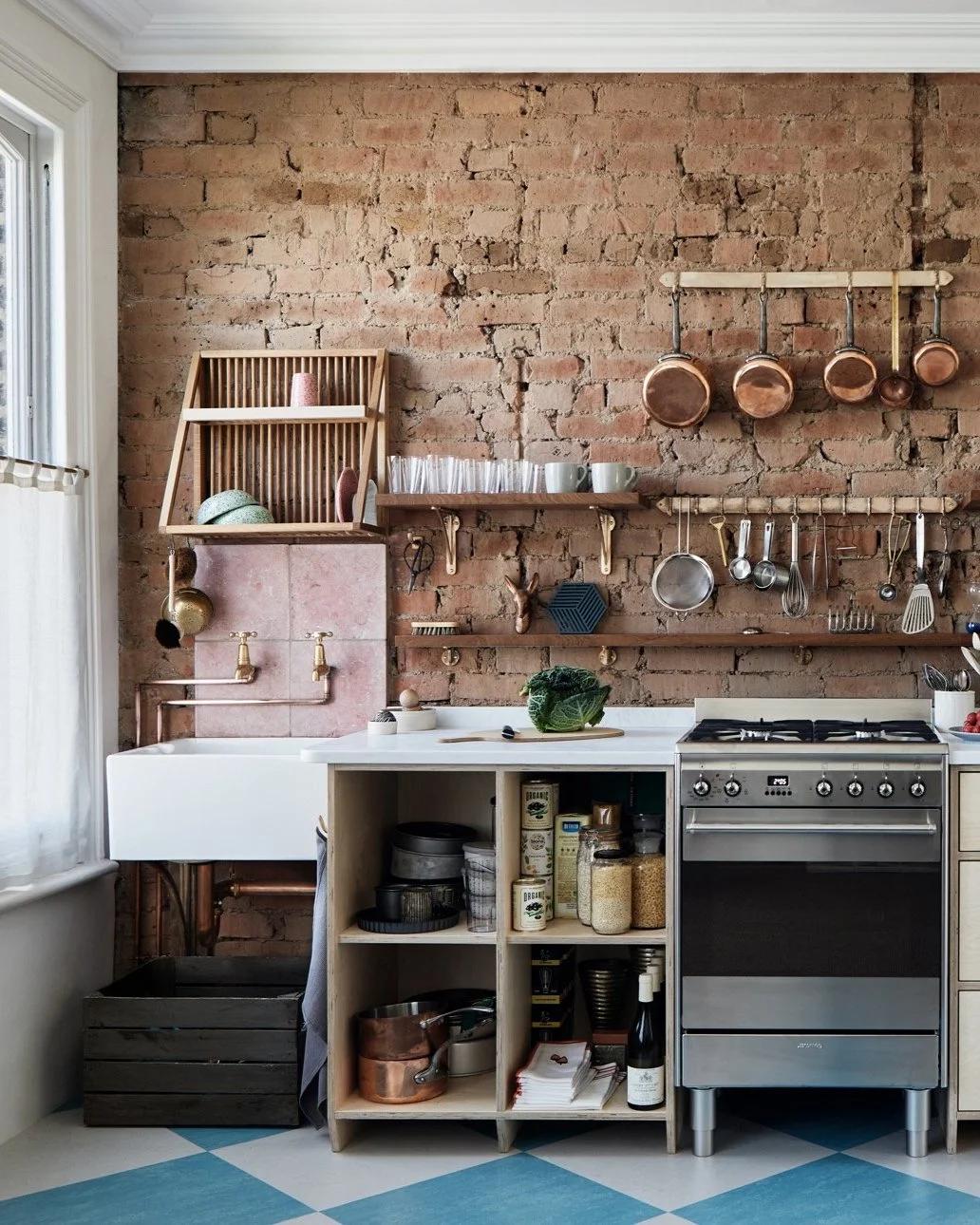 Cast Bronze Sink Brackets – Small, Medium & Large in an industrial kitchen, wide shot. Belfast sink on the left by a window, supported by a small bracket, next to plywood units with a marble surface.
