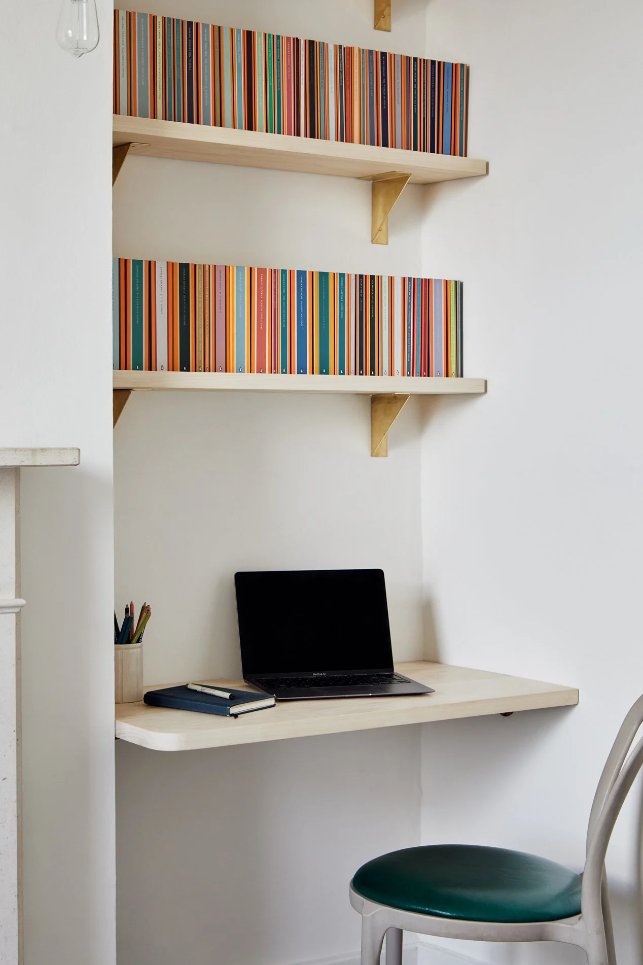 Side view of two timber shelves supported by brass folded brackets, with a matching timber desk below. The linen wash wall enhances the natural tones of the wood and unlacquered brass.