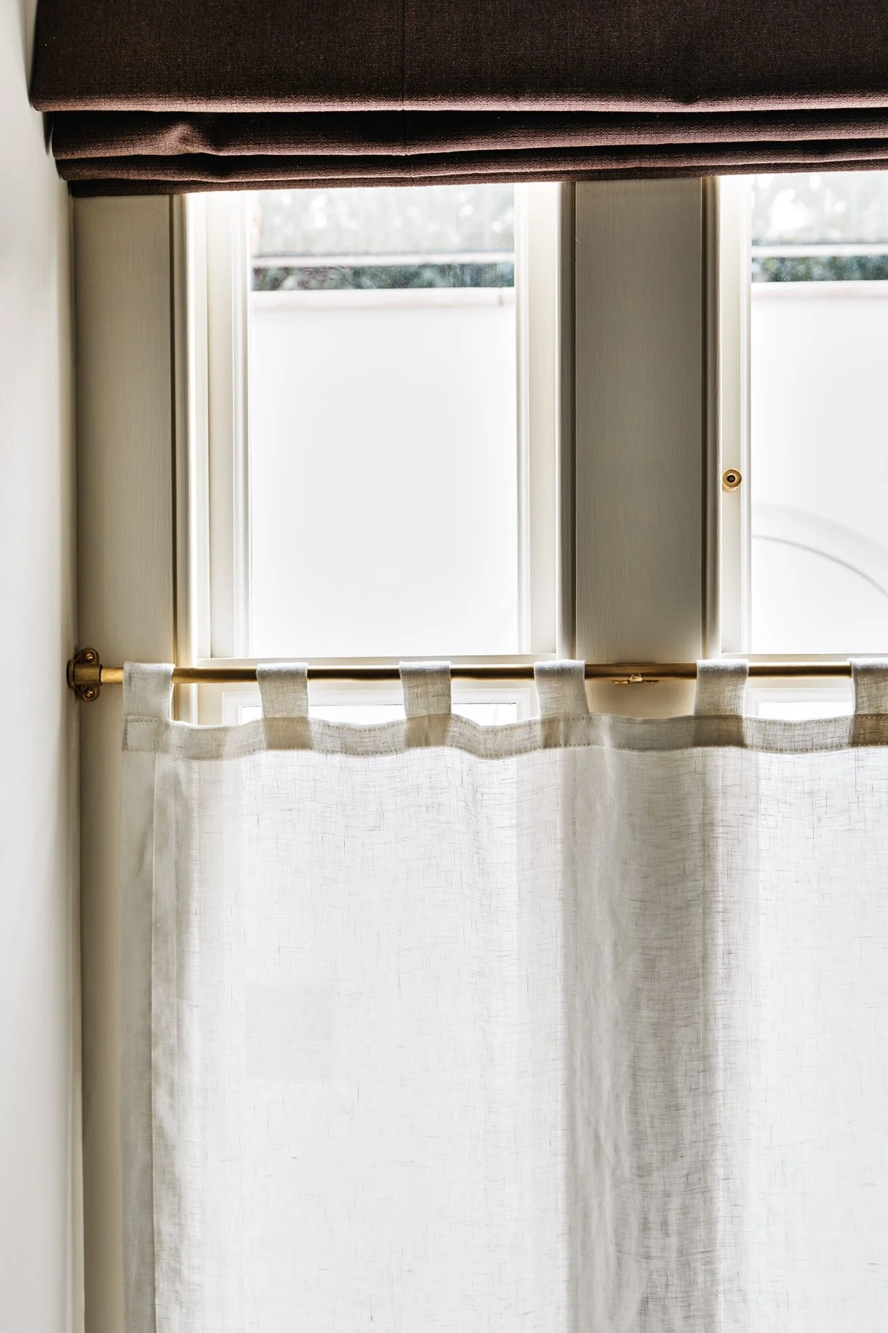 Unlacquered Brass Café Curtain Rail Set close-up of left side of triple box sash showing brass rail, café curtain end bracket, and linen curtain hanging with self-fabric loops