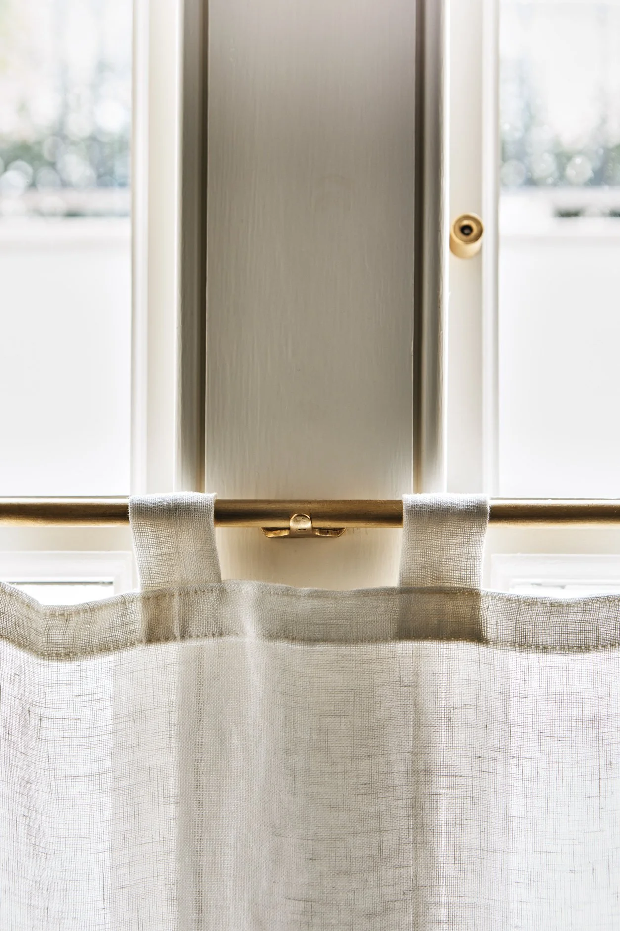Unlacquered Brass Café Curtain Rail Set with Recessed Brackets close-up of center bracket supporting brass rail with 1 fabric loop on each side, showing cross-hatch detail of fabric weave.