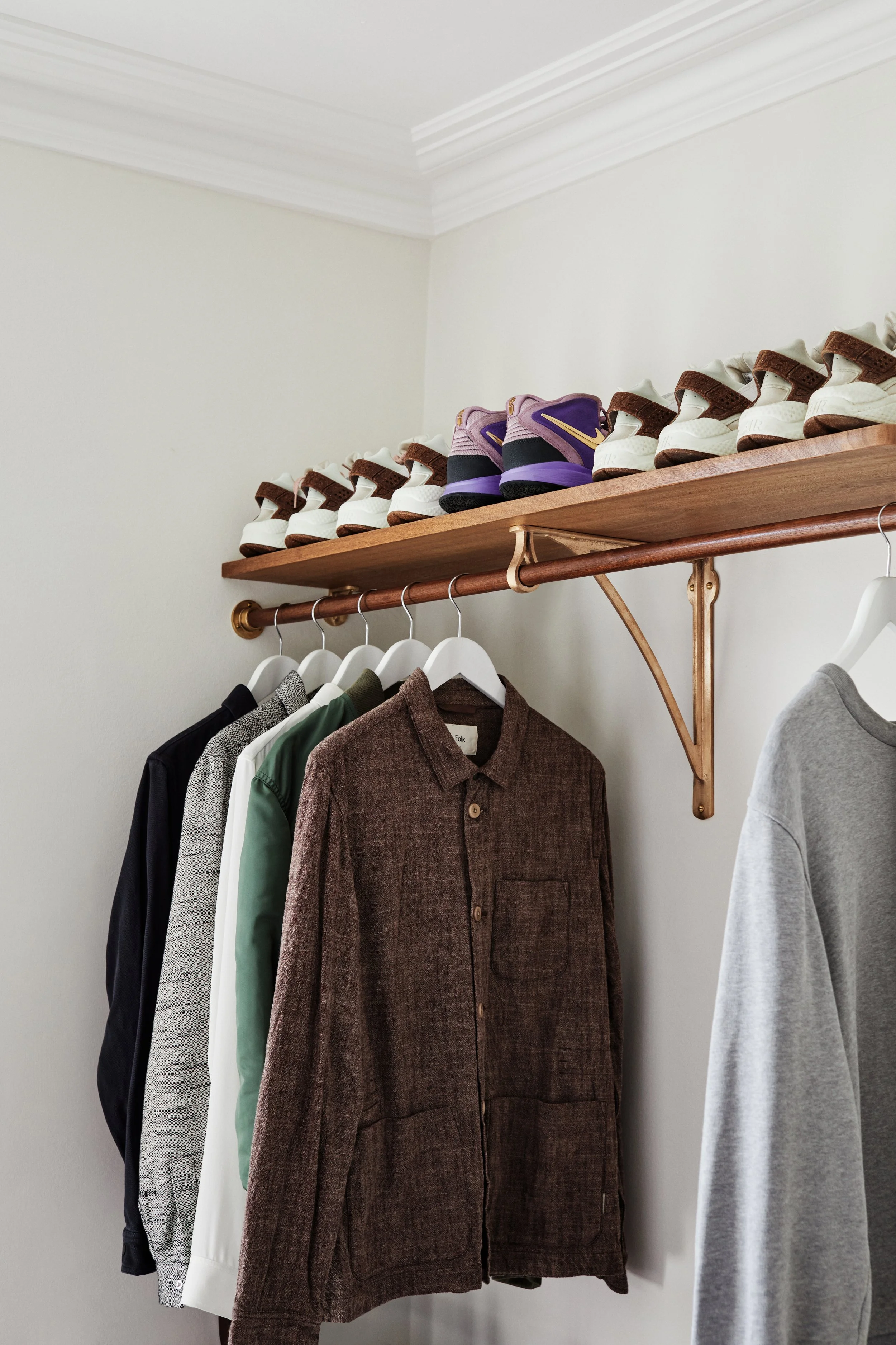 wardrobe bracket wide shot of closet with wardrobe bracket seen in the center, 5 jackets hanging, nike shoes on shelf above the bracket