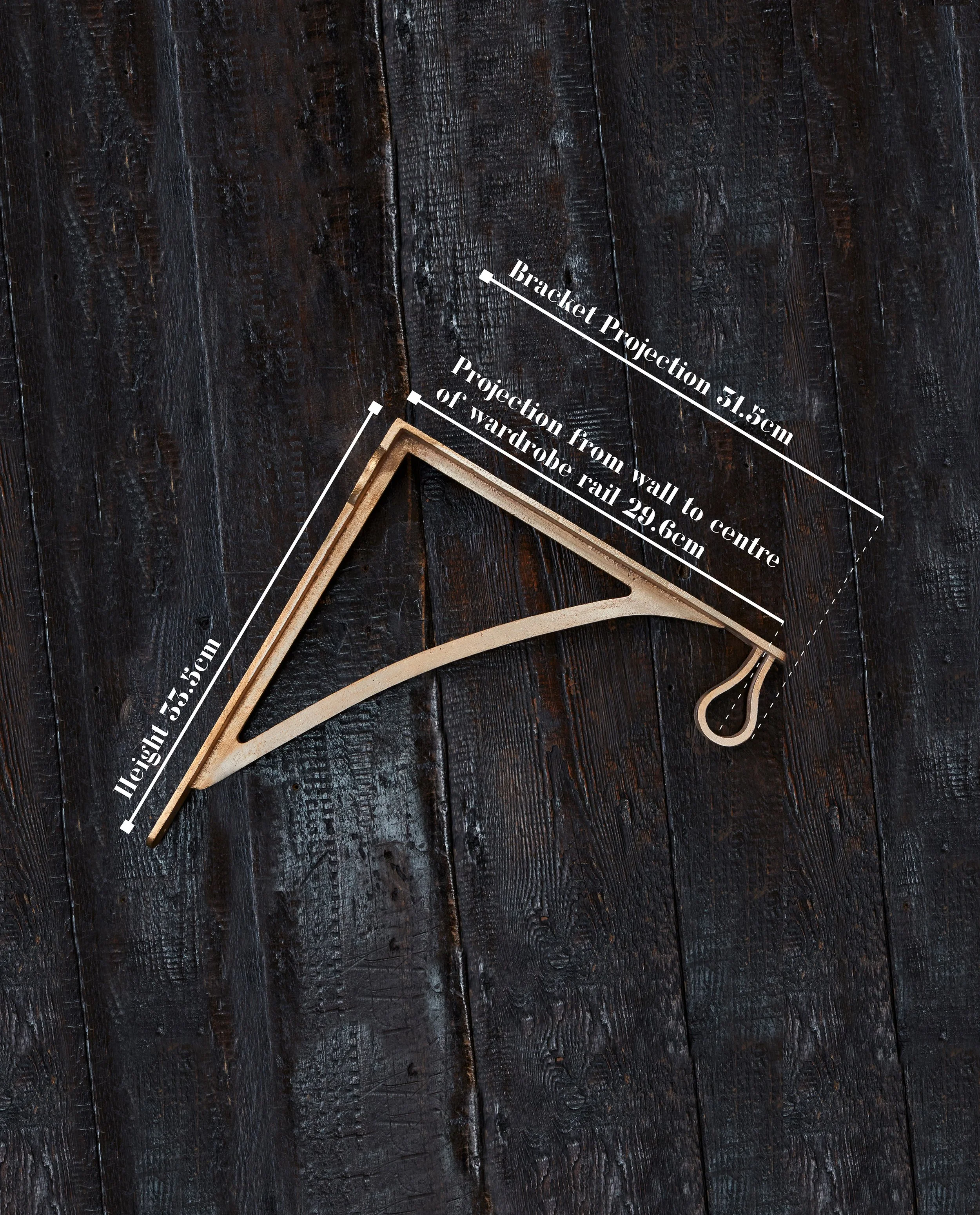wardrobe bracket laying flat on timber board made in raw bronze. overlay text shows height 33.5cm & projection 31.5cm.