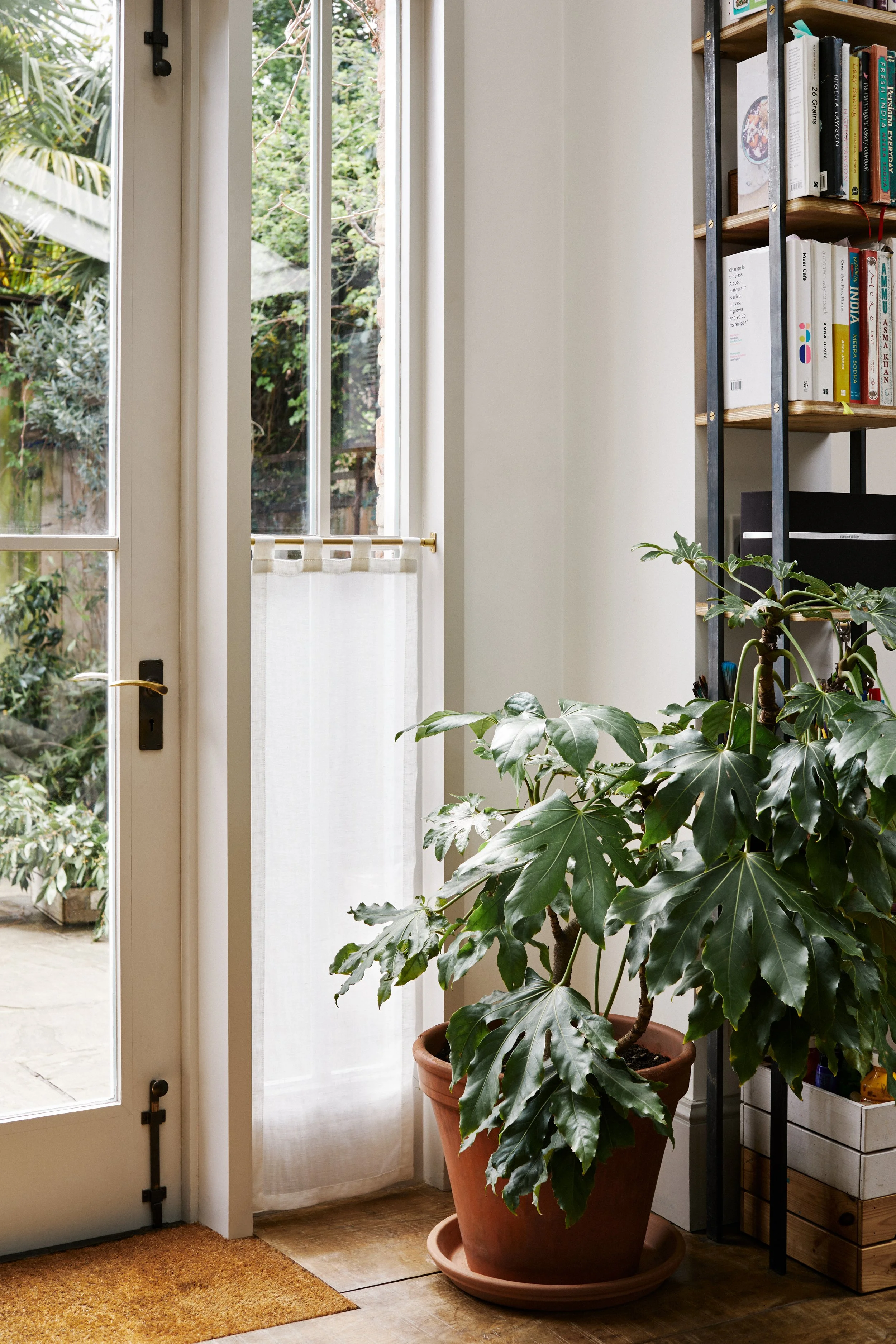 Unlacquered Brass Café Curtain Rail Set with Recessed Brackets – Mid shot of garden window with brass rail and linen curtain, lush green house plant in terracotta pot in foreground.