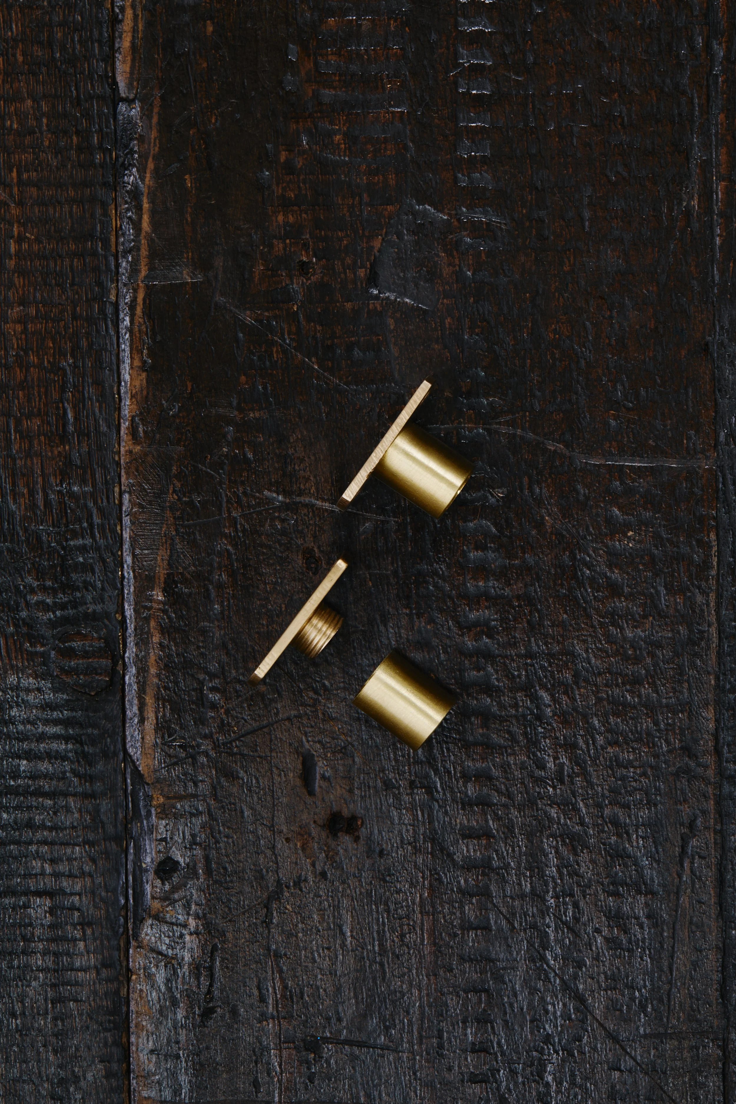 Recessed Café Curtain End Brackets - 2 end brackets laid out on an old, textured timber board, one unscrewed. Made in raw brass.