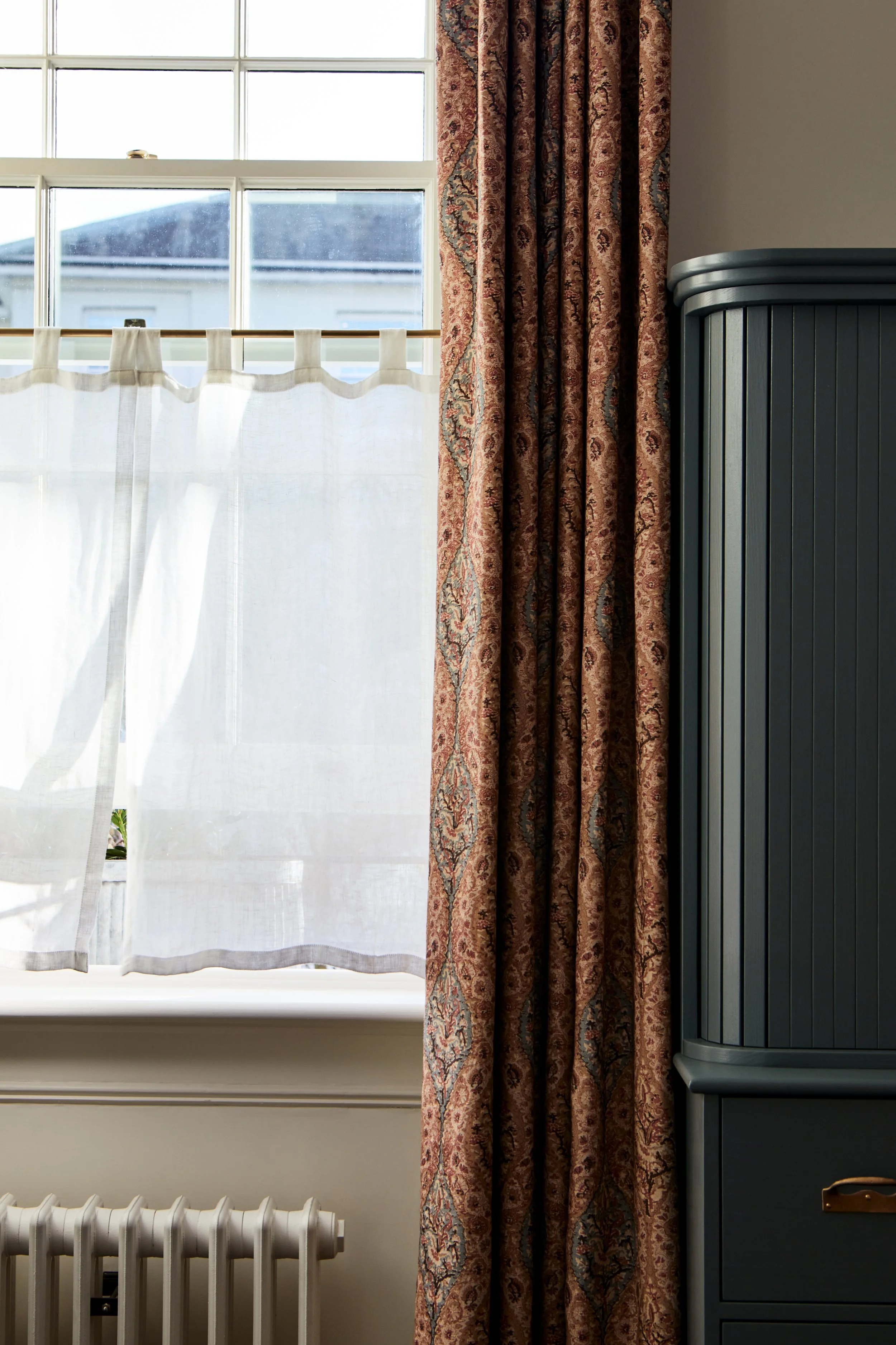 Recessed Café Curtain End Brackets mid shot of open window with cafe rail, linen curtain blowing in the wind, Robert Kime Avebury fabric curtain frames the right side.