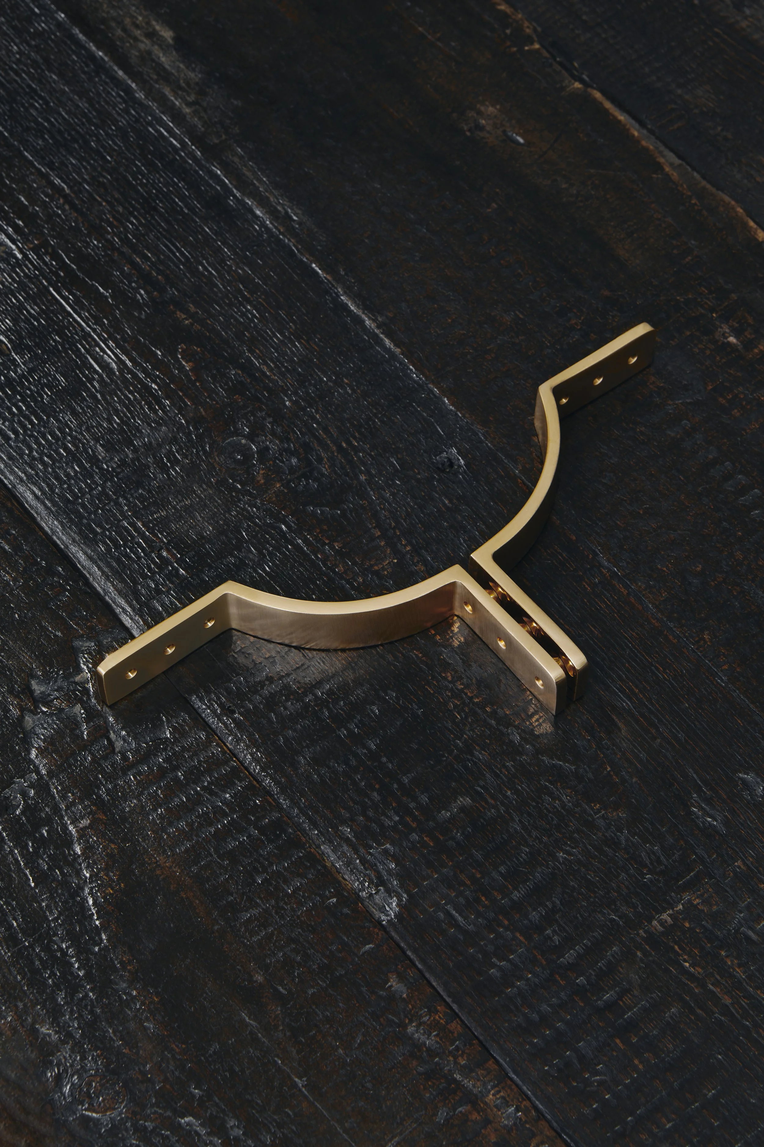 MORAY cupboard pulls, with the right and left handles sitting together to form a semi-circle, resting on a dark timber display board.