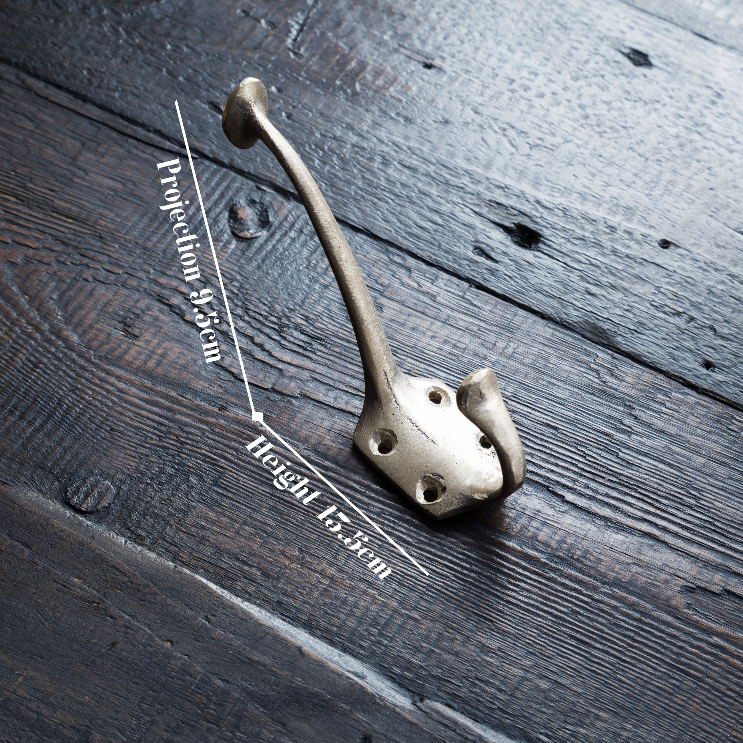 Jamie Coat Hook in cast bronze laying on a timber board. Overlaid text on the photo displays dimensions: height 13.5cm, projection 9.5cm.