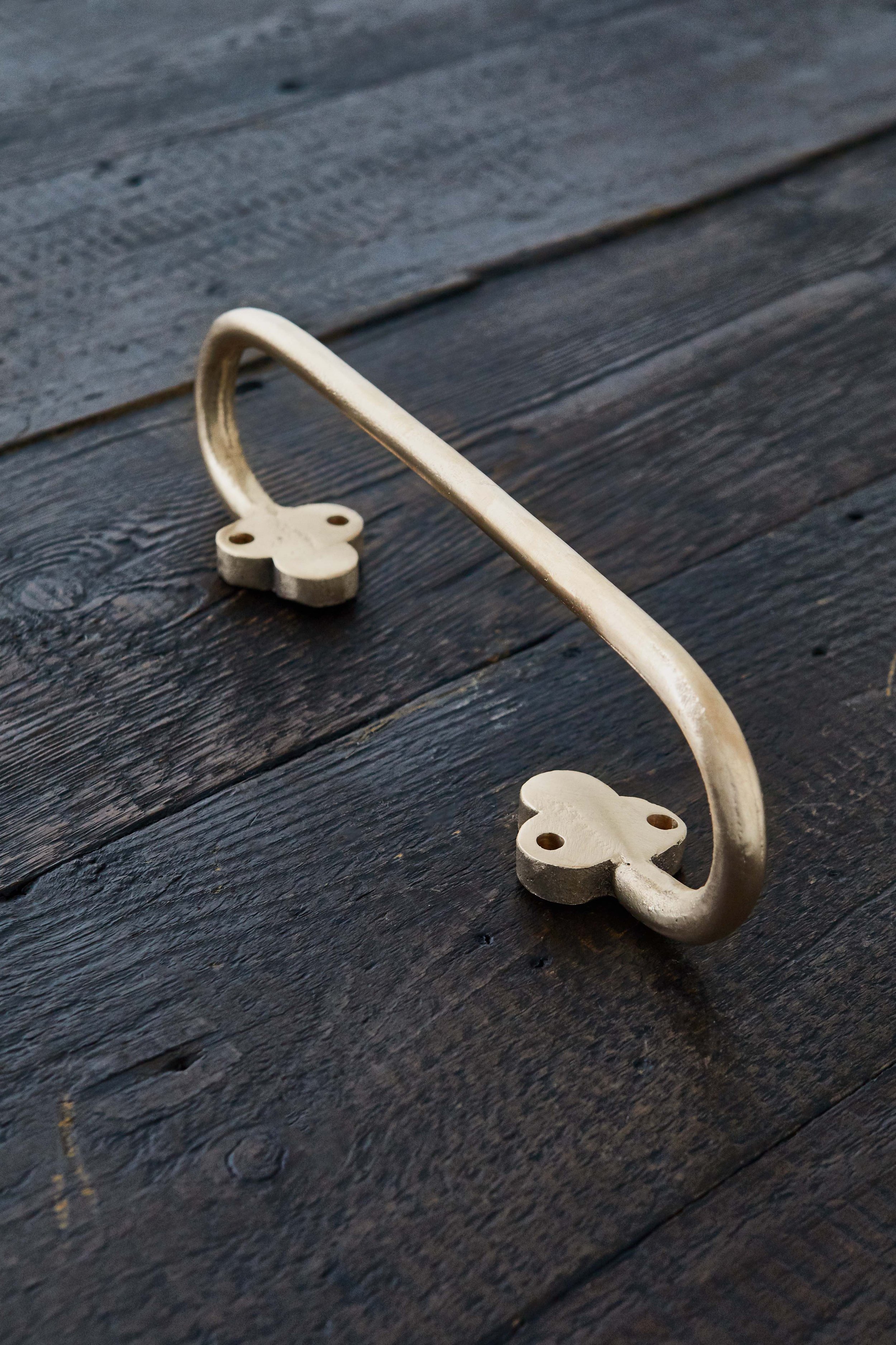 Hand Towel Rail, Cast Bronze solid 1/4 brass rod bent into an elongated oval, with trèfle emblems at the ends. Fixing holes drilled in the trèfle, sitting on a wooden board. Made in raw bronze.