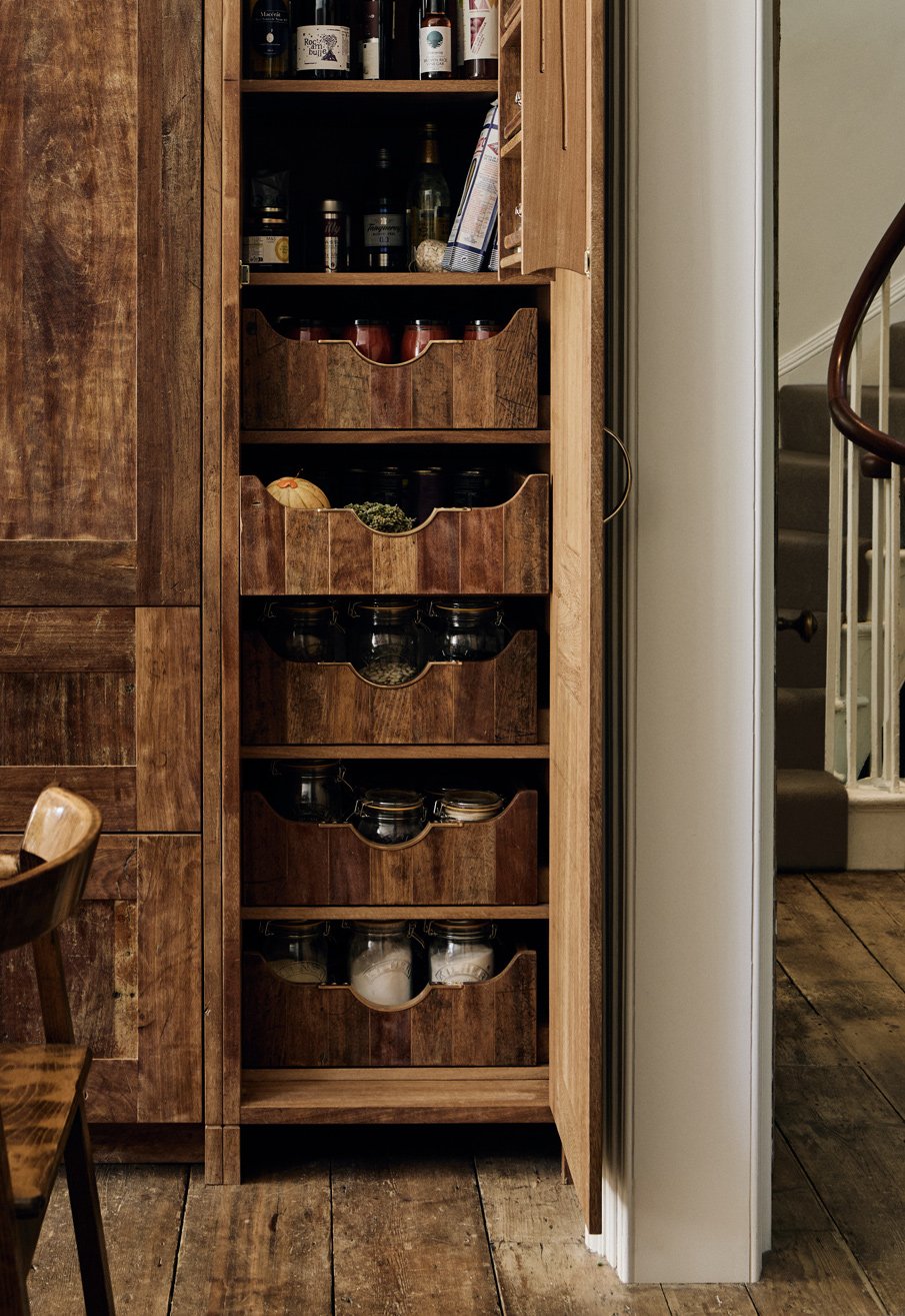 Wide photograph of 5 fitted Moray drawer pulls on internal drawers in a reclaimed iroko kitchen larder cupboard full of food, with the larder door open and food visible inside.