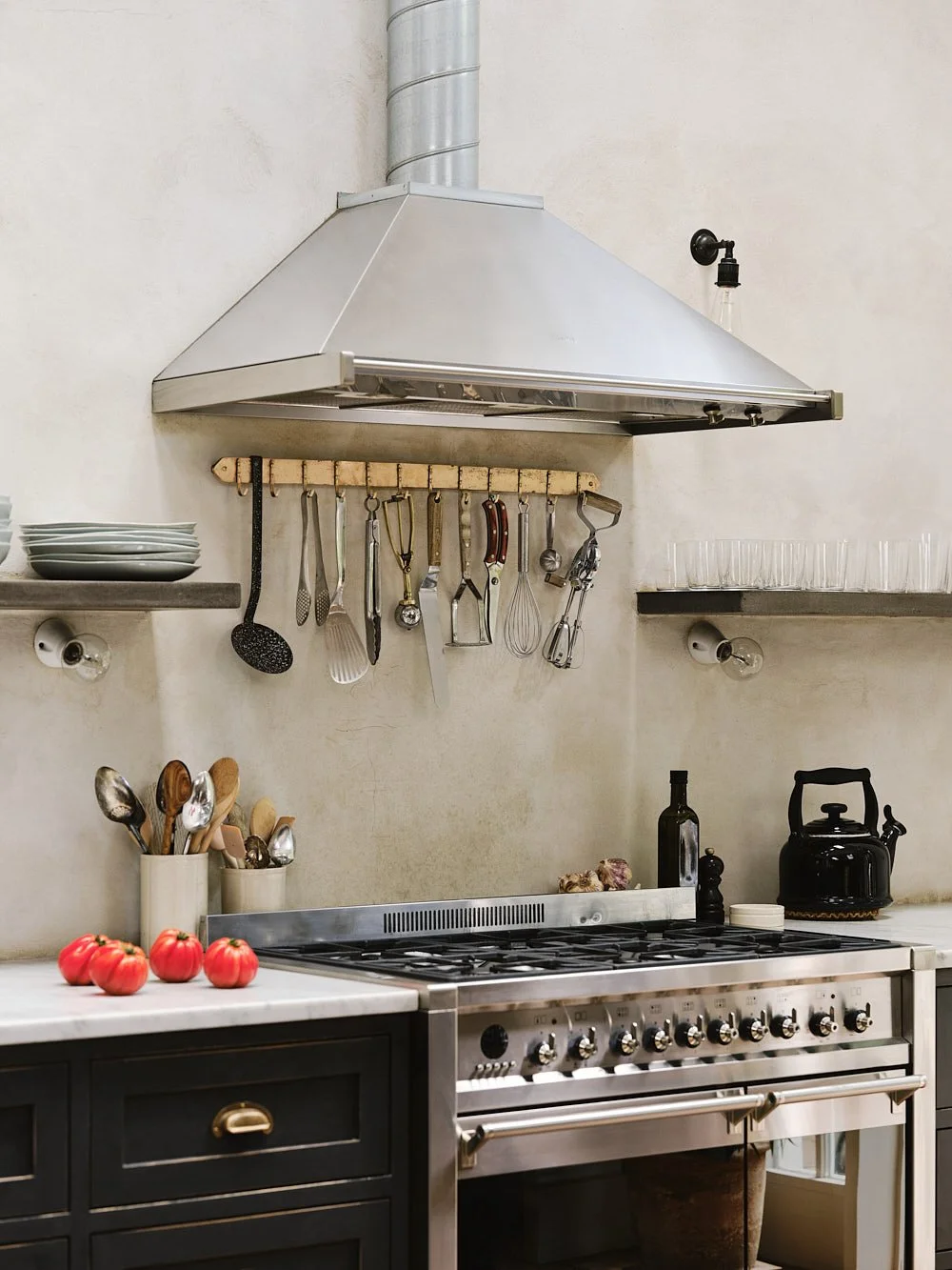 Mid-range view of the bronze utensil rack mounted in the kitchen, showing the sand-cast texture and practical hook layout.