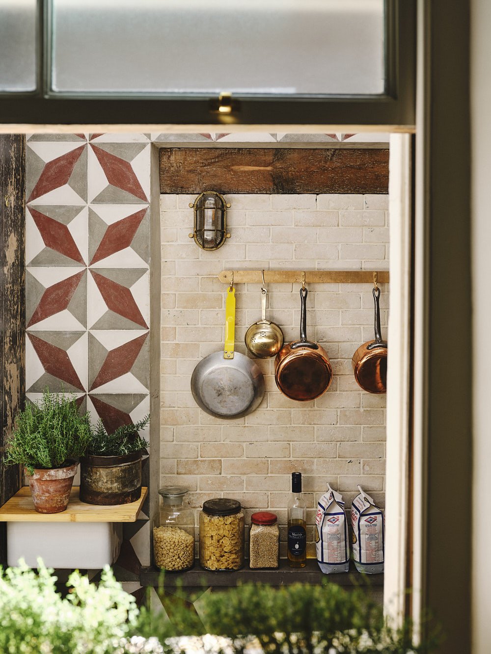 Wide larder view of the full sand-cast bronze pan rack in use, with pans displayed and the unlacquered finish visible.