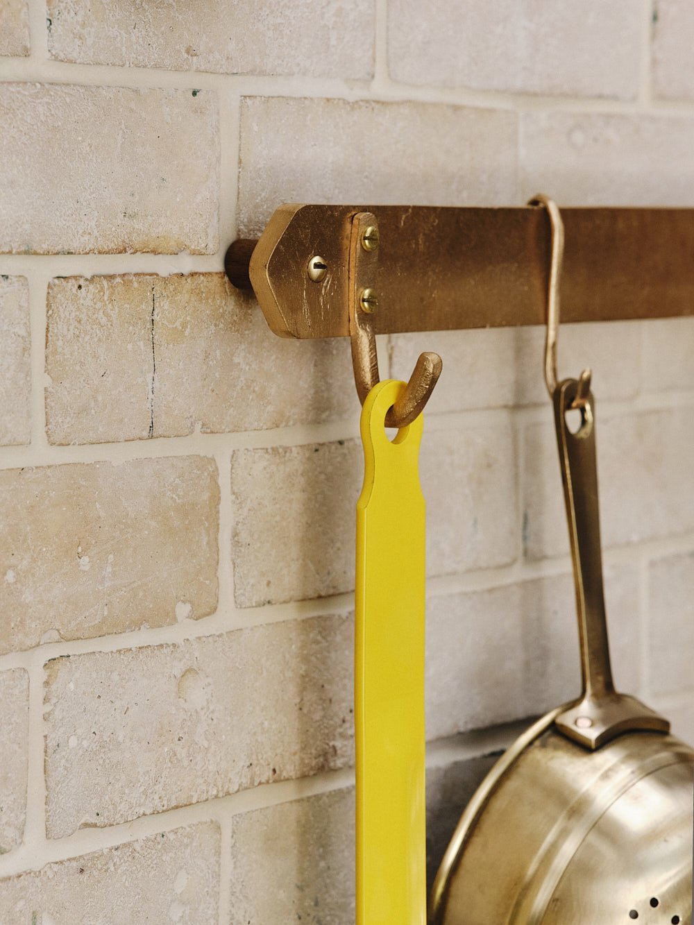 Close-up of the end of the sand-cast bronze pan rack with a single pan hanging from the fixed hook.
