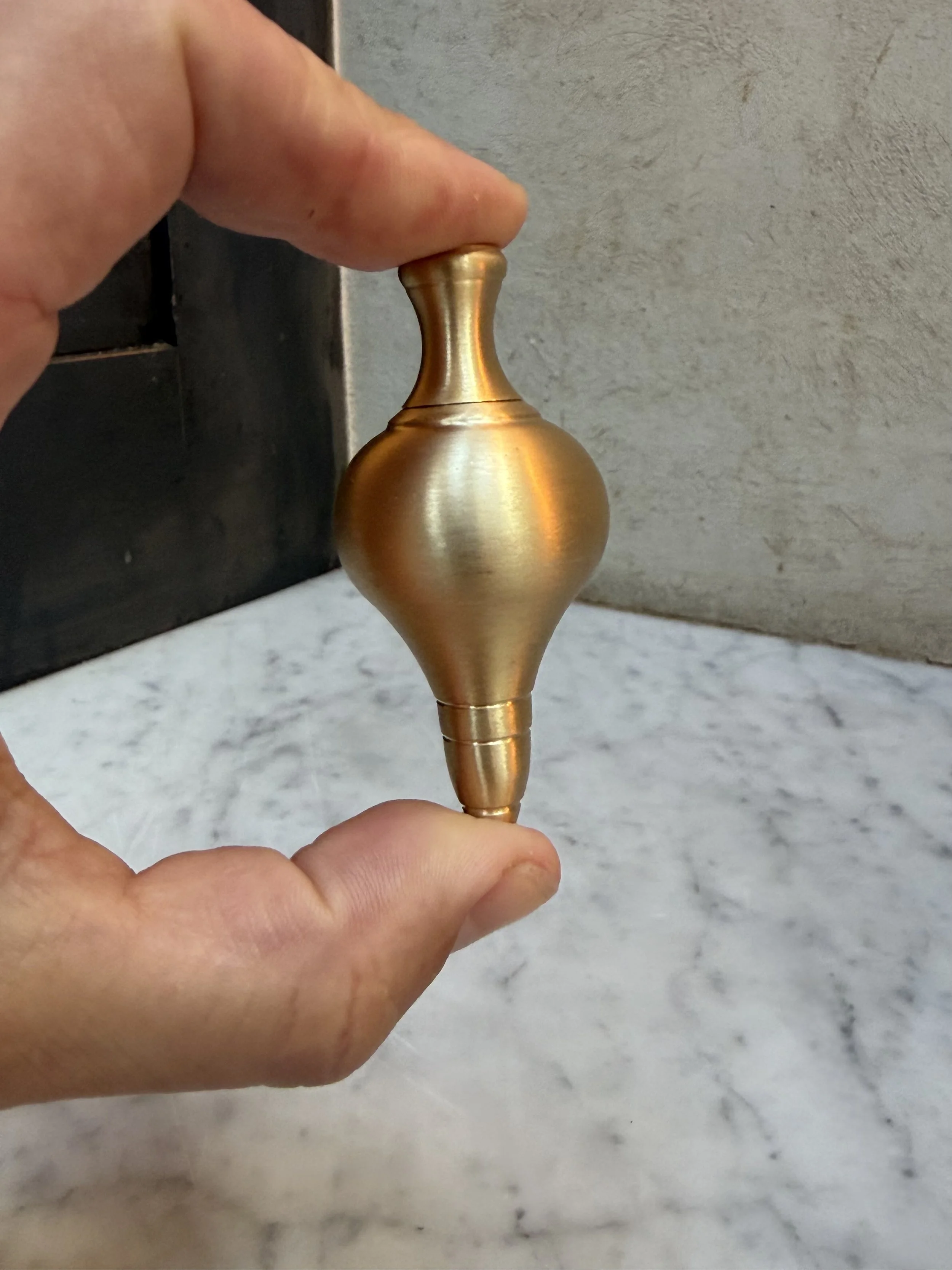 unlacquered-brass-cord-weight-held-in-hand.jpg