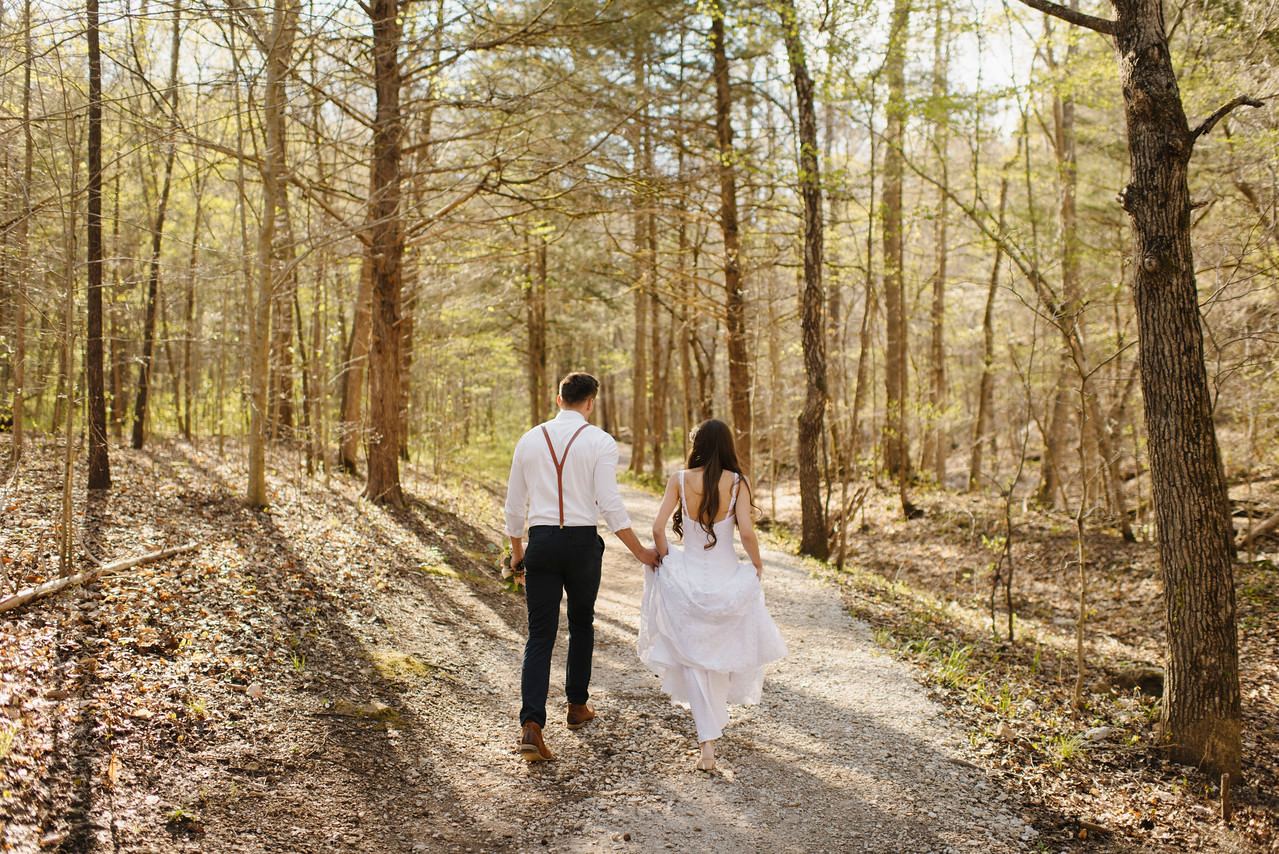 A bride and groom walk through the woods by the Buffalo River with Arkansas Adventure Destination Photographer Colby and Jess