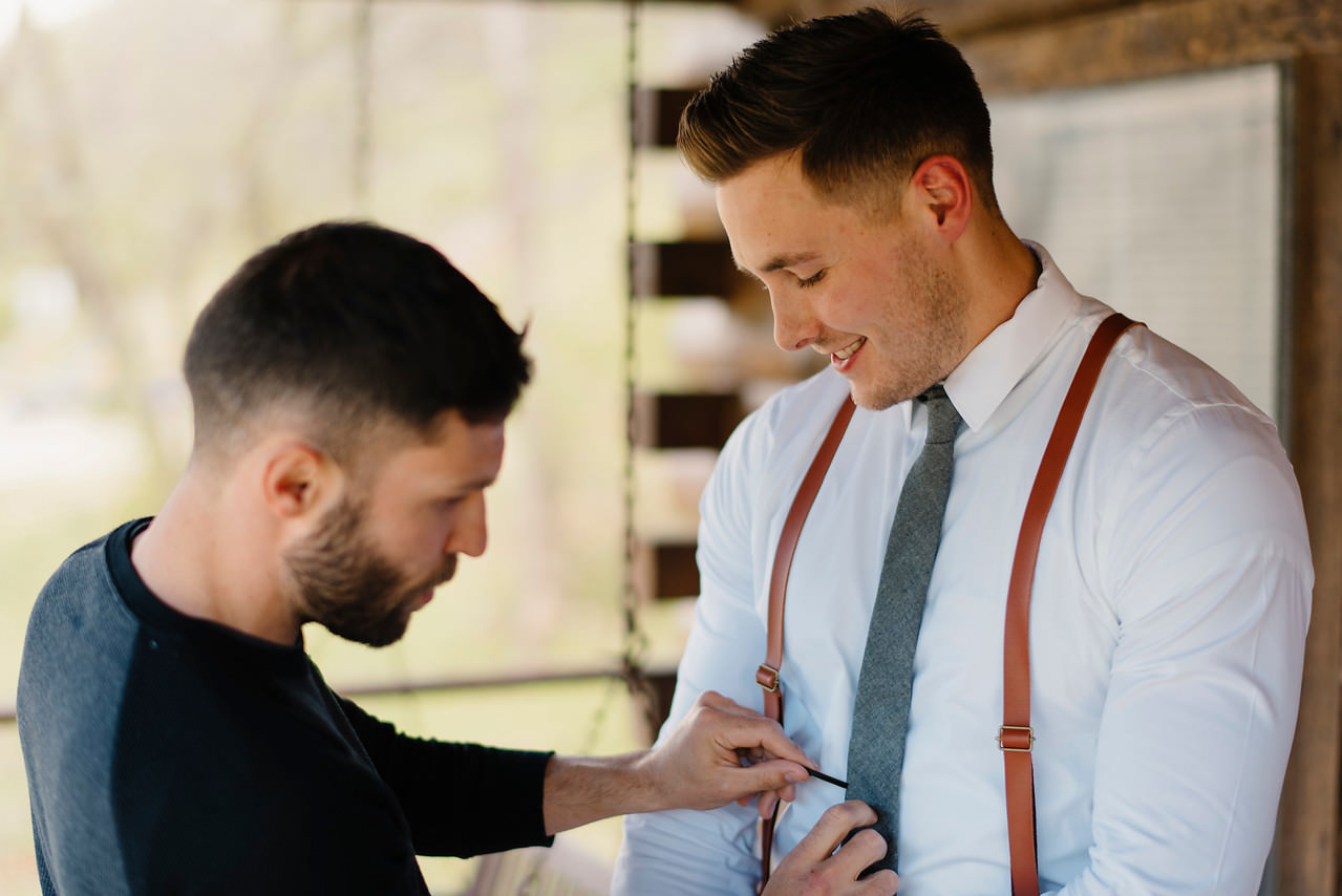 A groom's brother helps him get ready for his Buffalo River Wedding by Ozarks Adventure Destination Elopement Photographers Colby and Jess