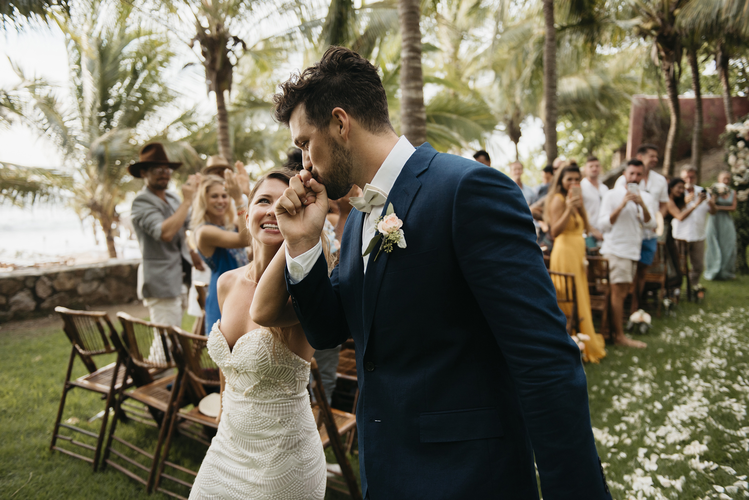 Groom kisses his brides hand as they walk down the aisle during Sayulita Wedding by Puerto Vallarta Elopement photographer Colby and Jess colbyandjess.com