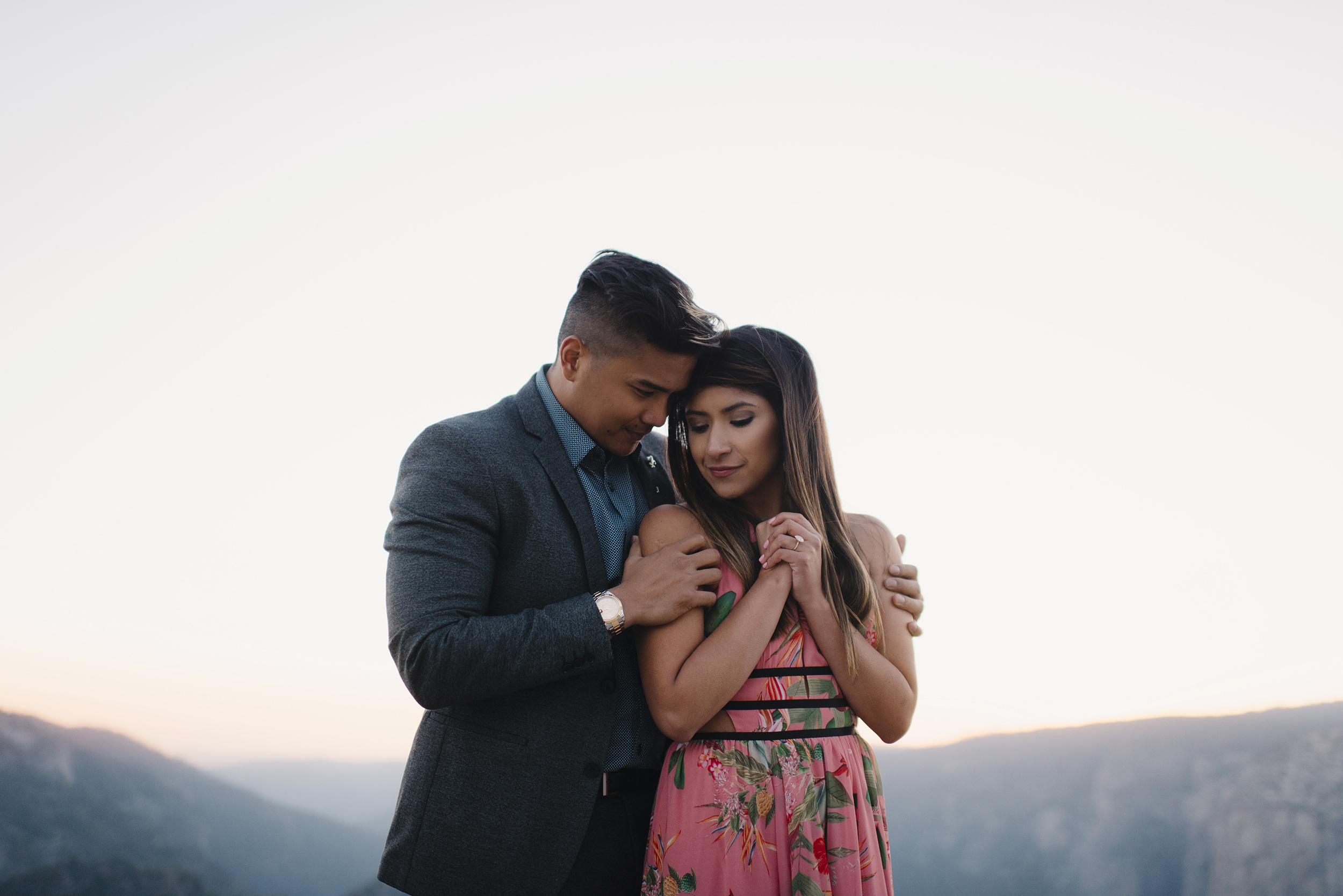 Engaged couple cuddles at sunset at Taft Point during engagement photography by Yosemite Wedding Photographers Colby and Jess colbyandjess.com