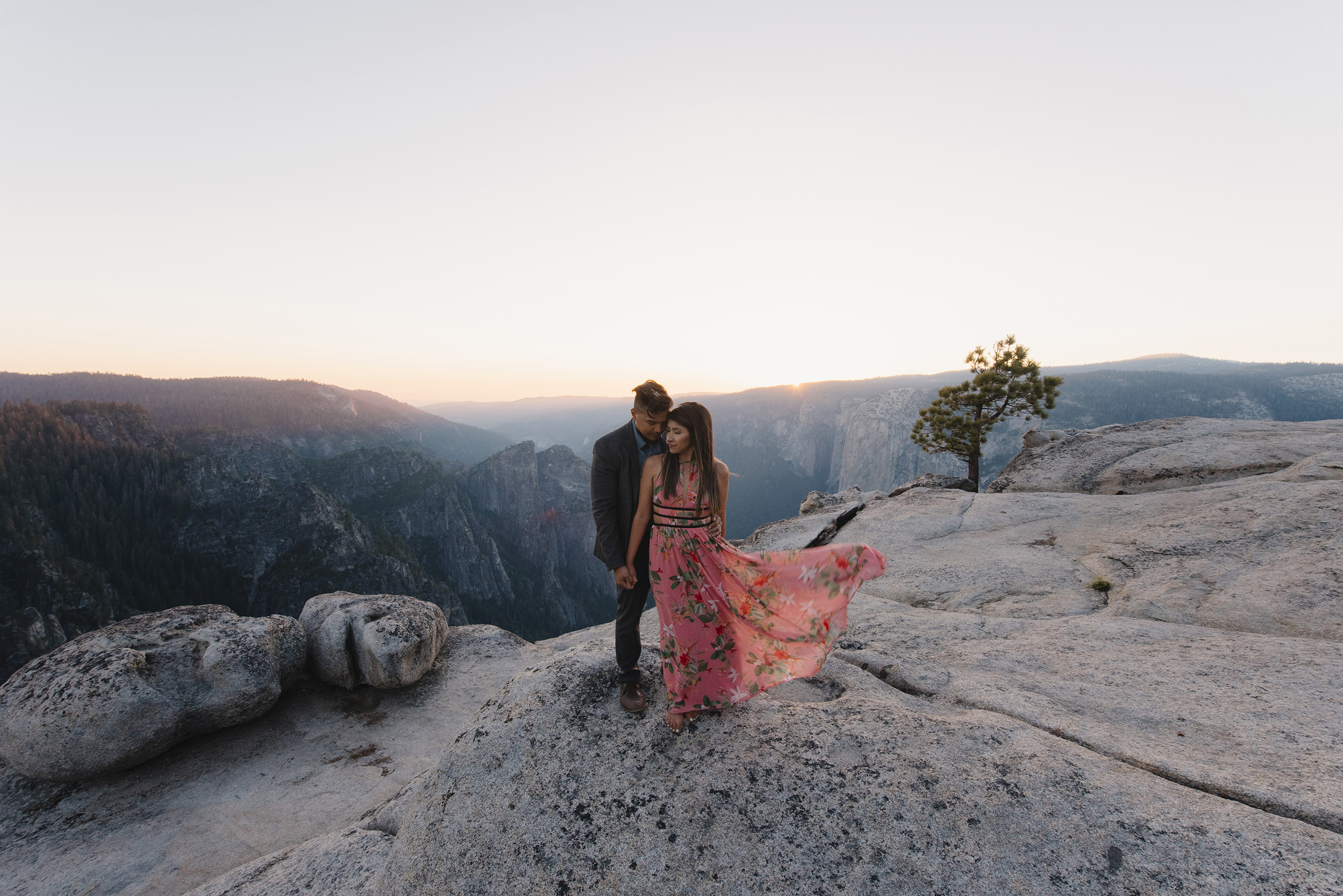 Bride to be's dress blows in the wind at sunset during their Taft Point Adventure photography session by Yosemite Wedding Photographers Colby and Jess colbyandjess.com