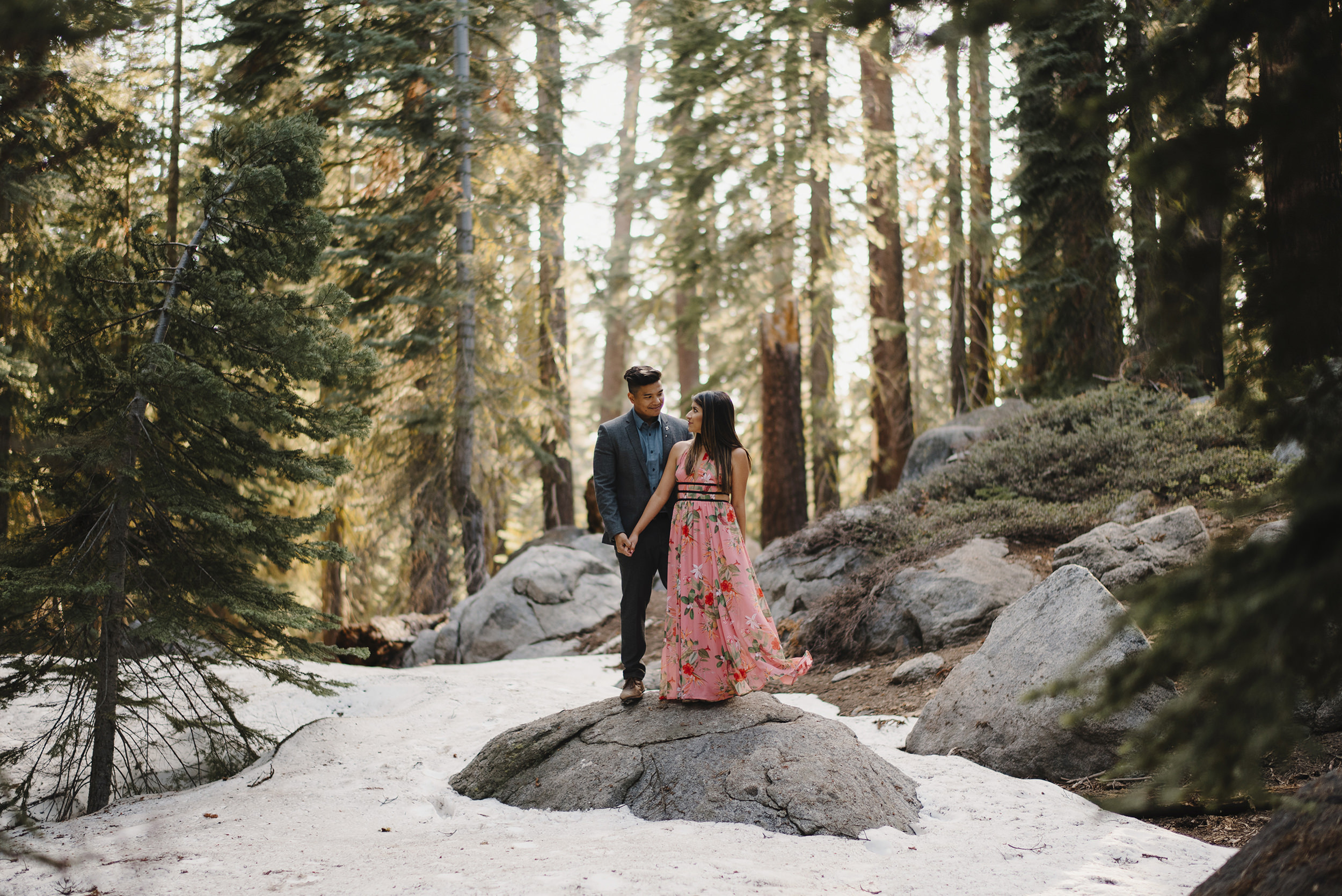 Engaged couple smile at each other along snow covered Taft Point Trail in Yosemite 