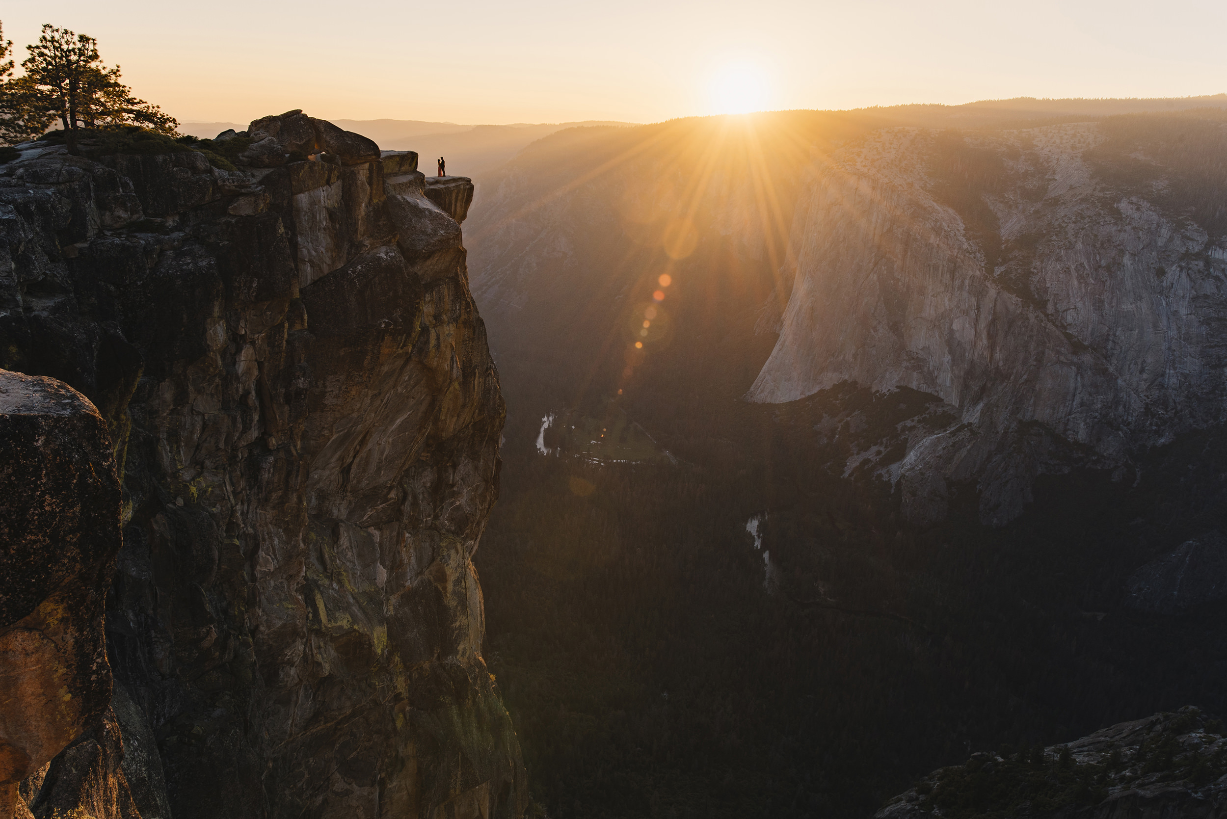 Engaged couple watches the sun set on Taft Point in Yosemite National Park / Adventure engagement photography by Colby and Jess Photography / colbyandjess.com