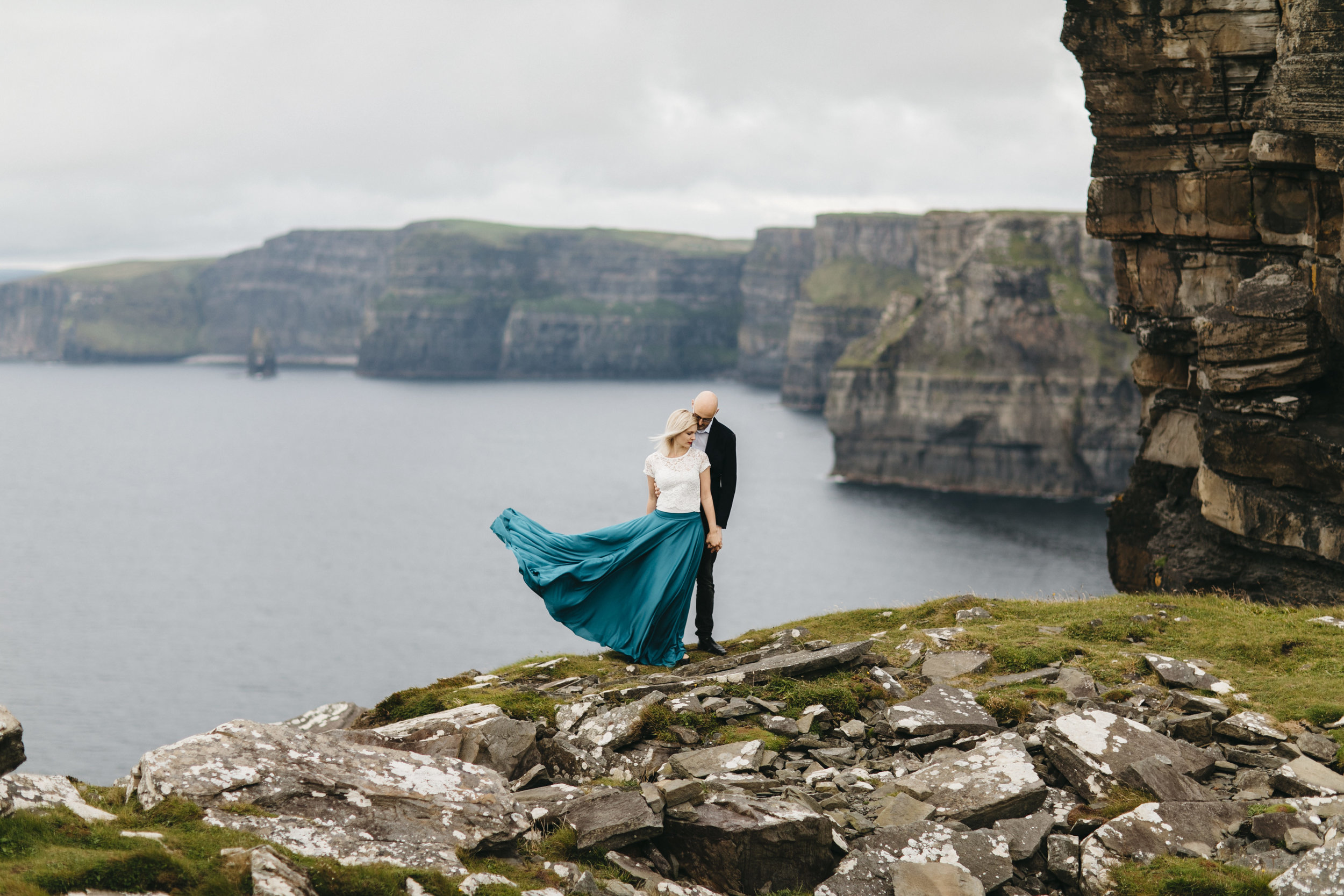 Married couple stands on edge of Cliffs of Moher by Adventurous Ireland Elopement Photographer Colby and Jess