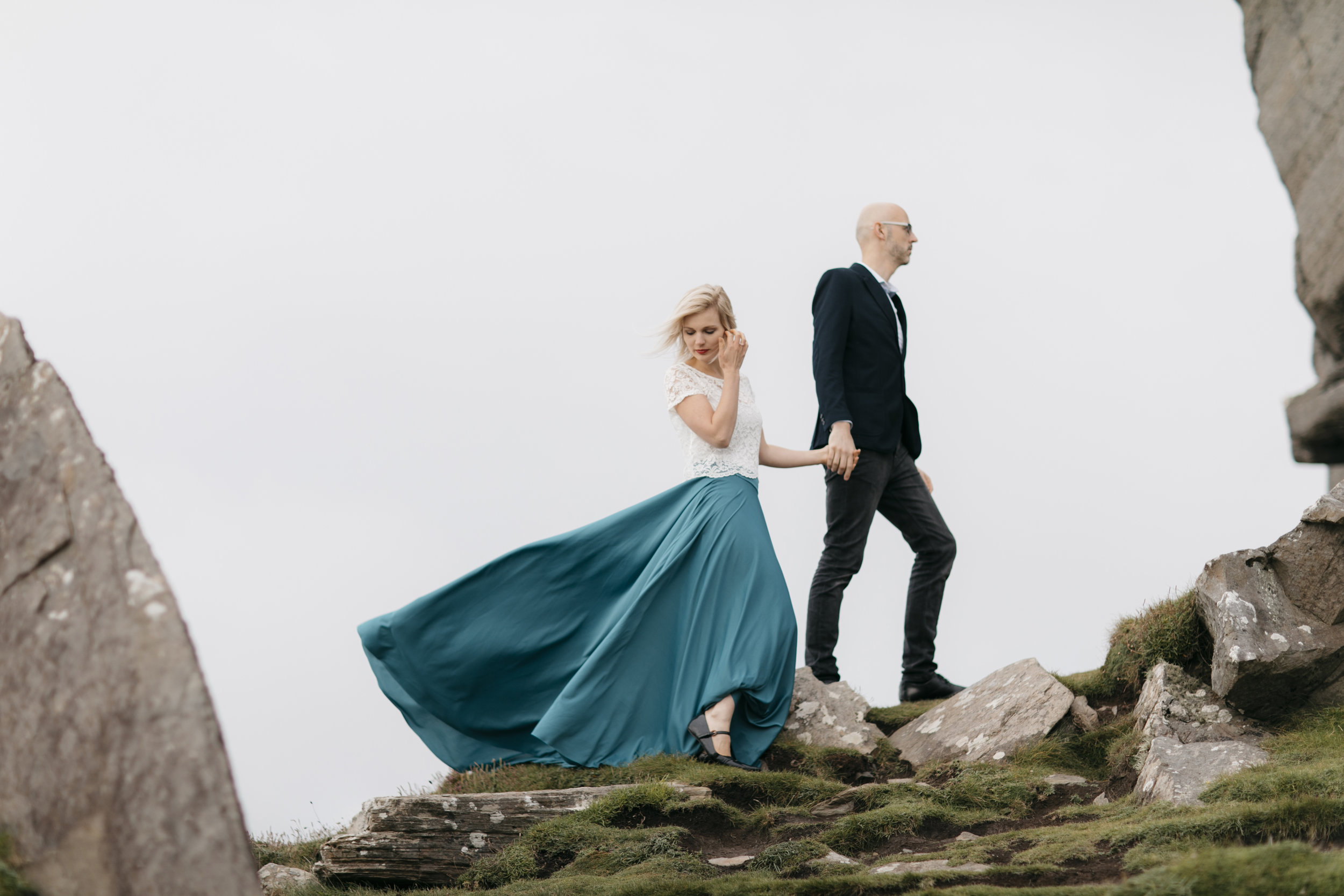 Couple walk on rocks at Cliffs of Moher during adventure photography session by ireland elopement photographers Colby and Jess