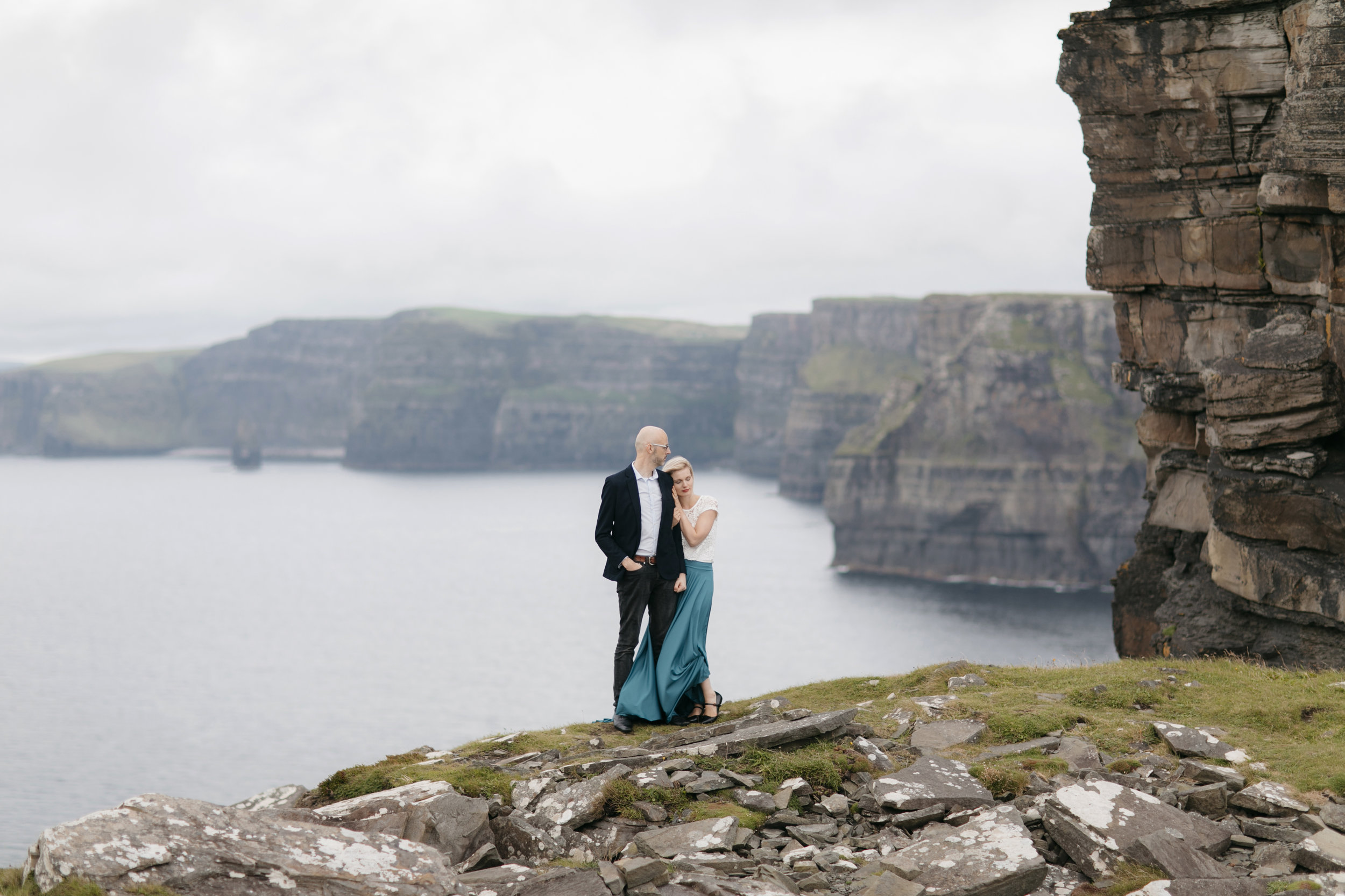 Lovely couple snuggle up at Cliffs of Moher during adventure photography session by Ireland elopement photographer Colby and Jess 