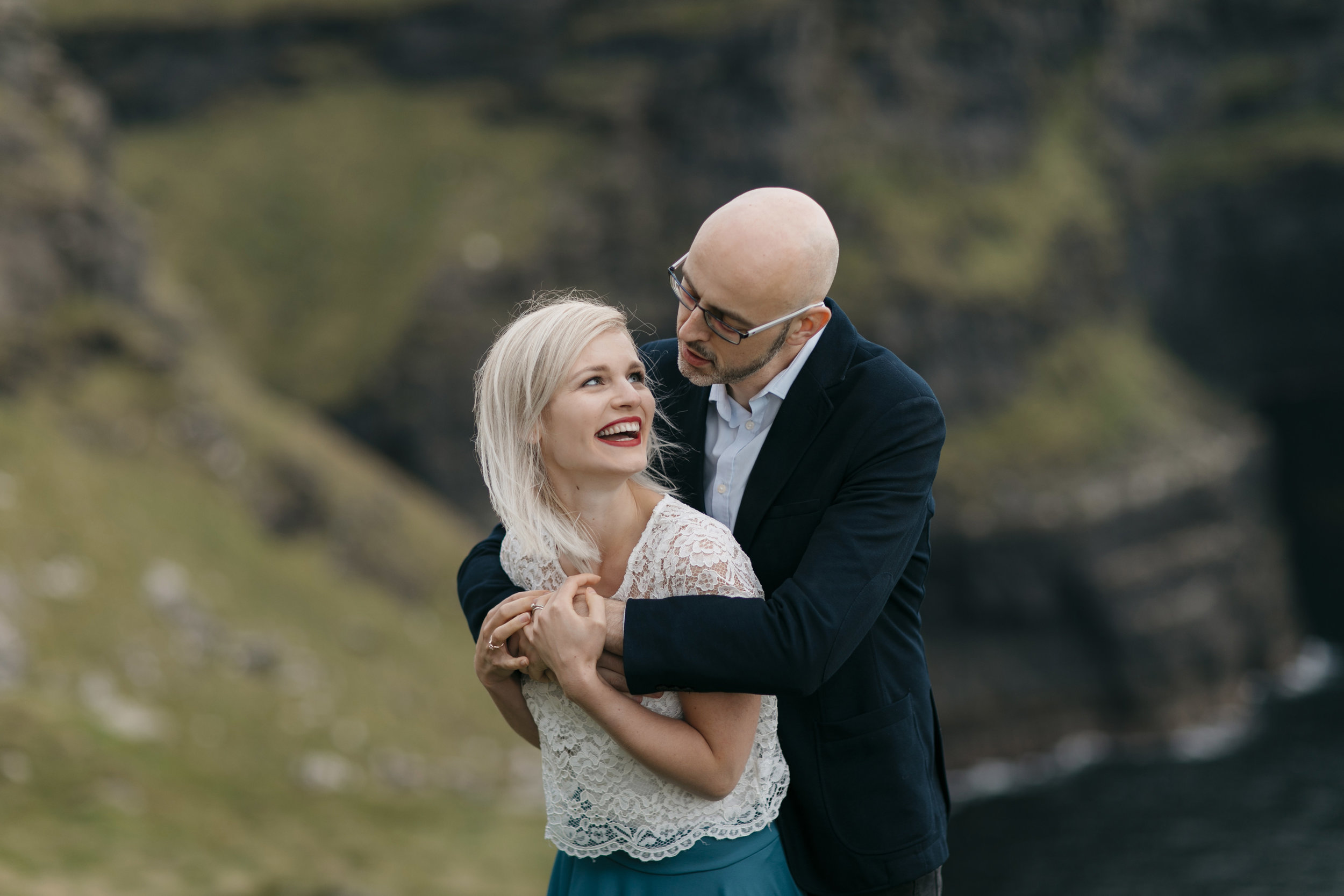 Adorable couple laugh while being photographed at Cliffs of Moher by Adventure Wedding Photographer Colby and Jess