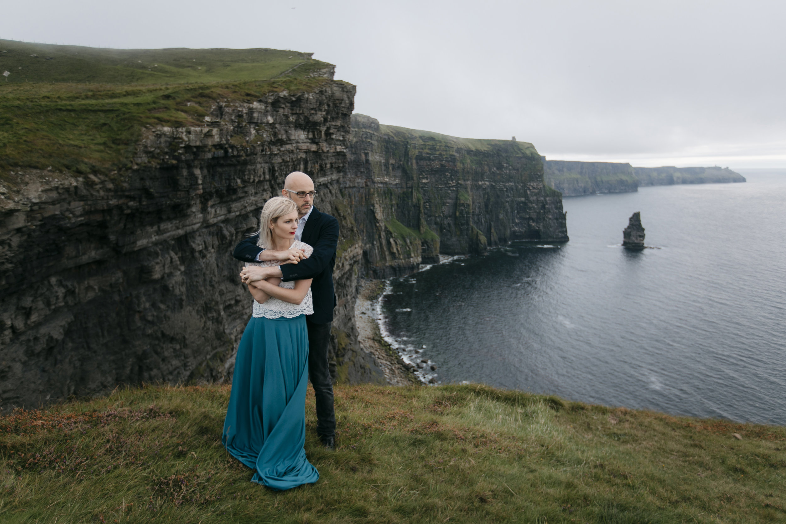 Married couple embraces at Cliffs of Moher during their epic photography session by Ireland Elopement photographer Colby and Jess