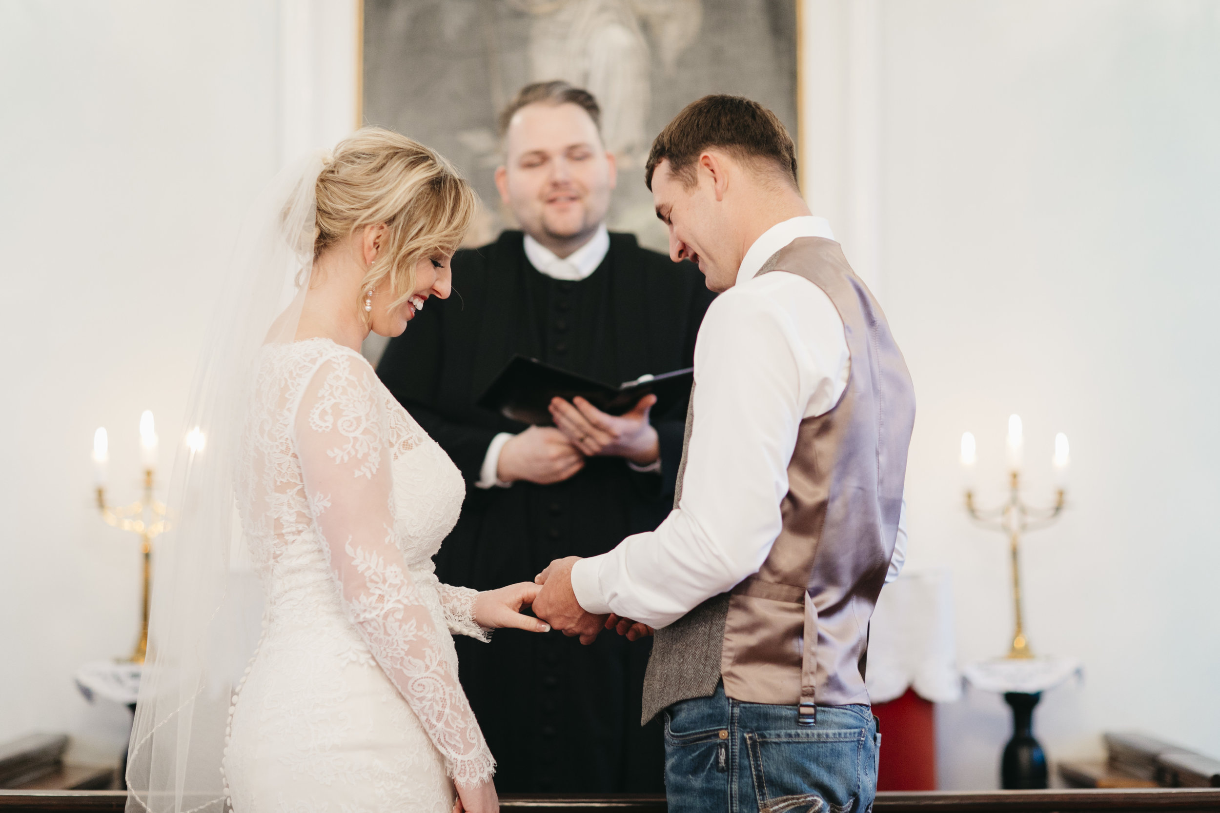 Groom slips the ring on his bride's finger during elopement ceremony in Hvalsneskirkja Church with their Iceland wedding photographers Colby and Jess.