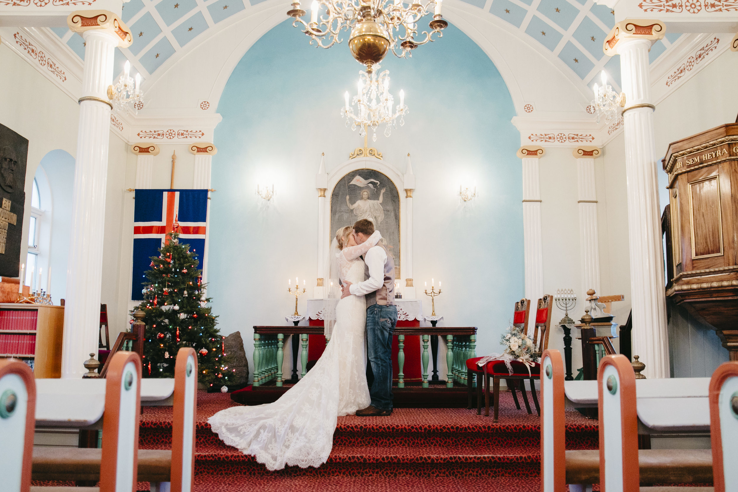 The bride and groom seal their vows with a kiss in Hvalsneskirkja Church while eloping in Iceland with their photographers Colby and Jess.