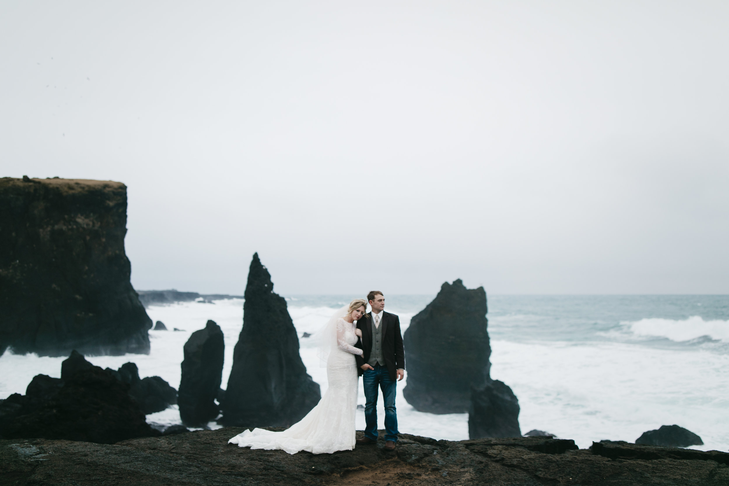 A lovely couple snuggles on the coast of Iceland during their elopement adventure session by photographers Colby and Jess, colbyandjess.com