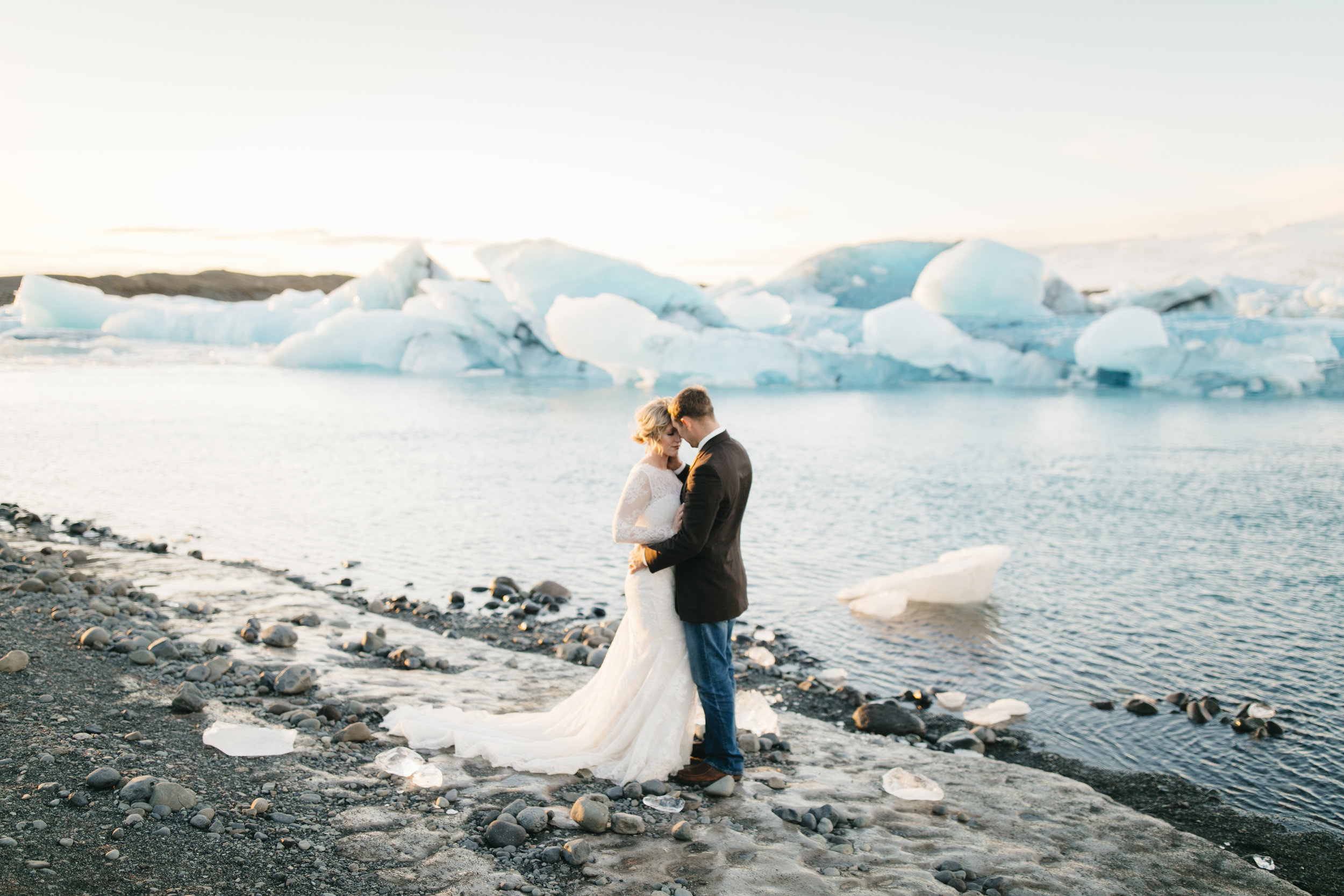 A man embraces his bride beside jokulsarlon glaciers during Iceland Elopement Photography session with Colby and Jess.