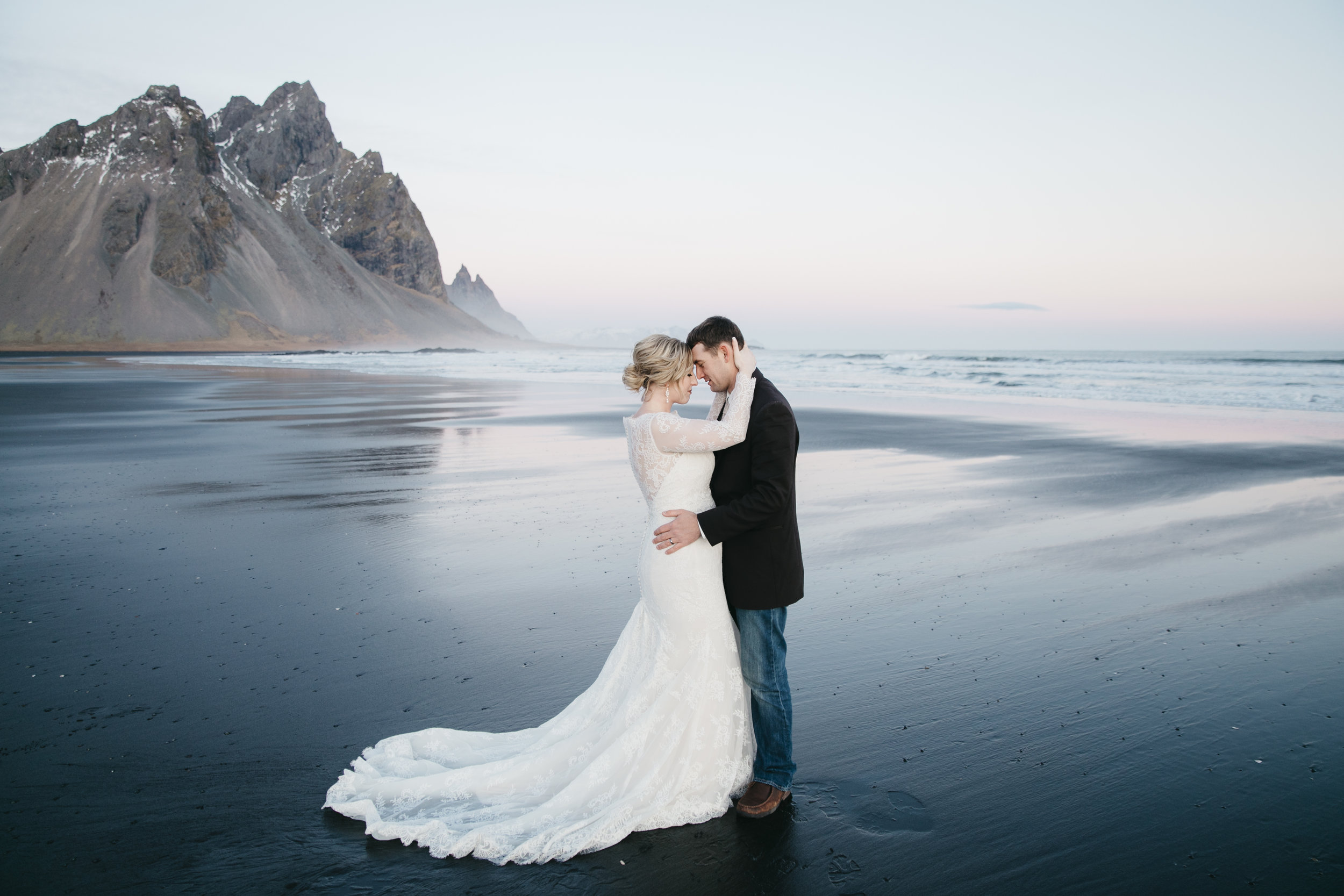 A couple embraces during elopement on the black sand beach in Vestrahorn with Iceland wedding photographers Colby and Jess.