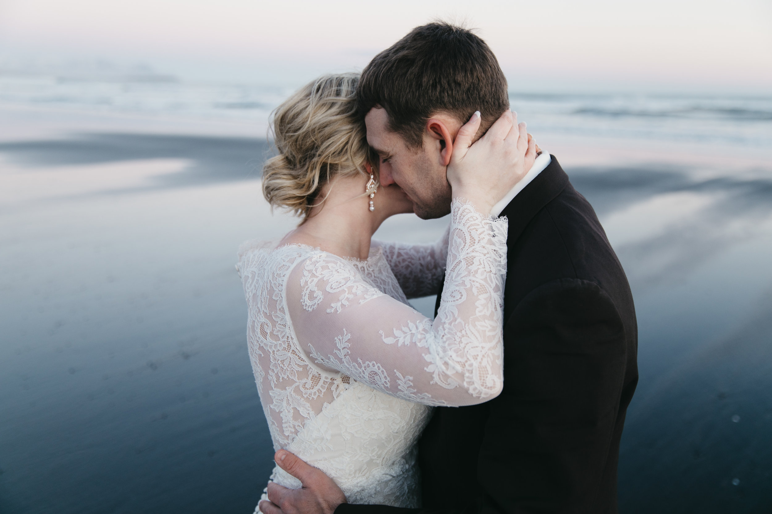 A couple snuggles on the black sand beach during iceland elopement ceremony with destination wedding photographers colby and jess.