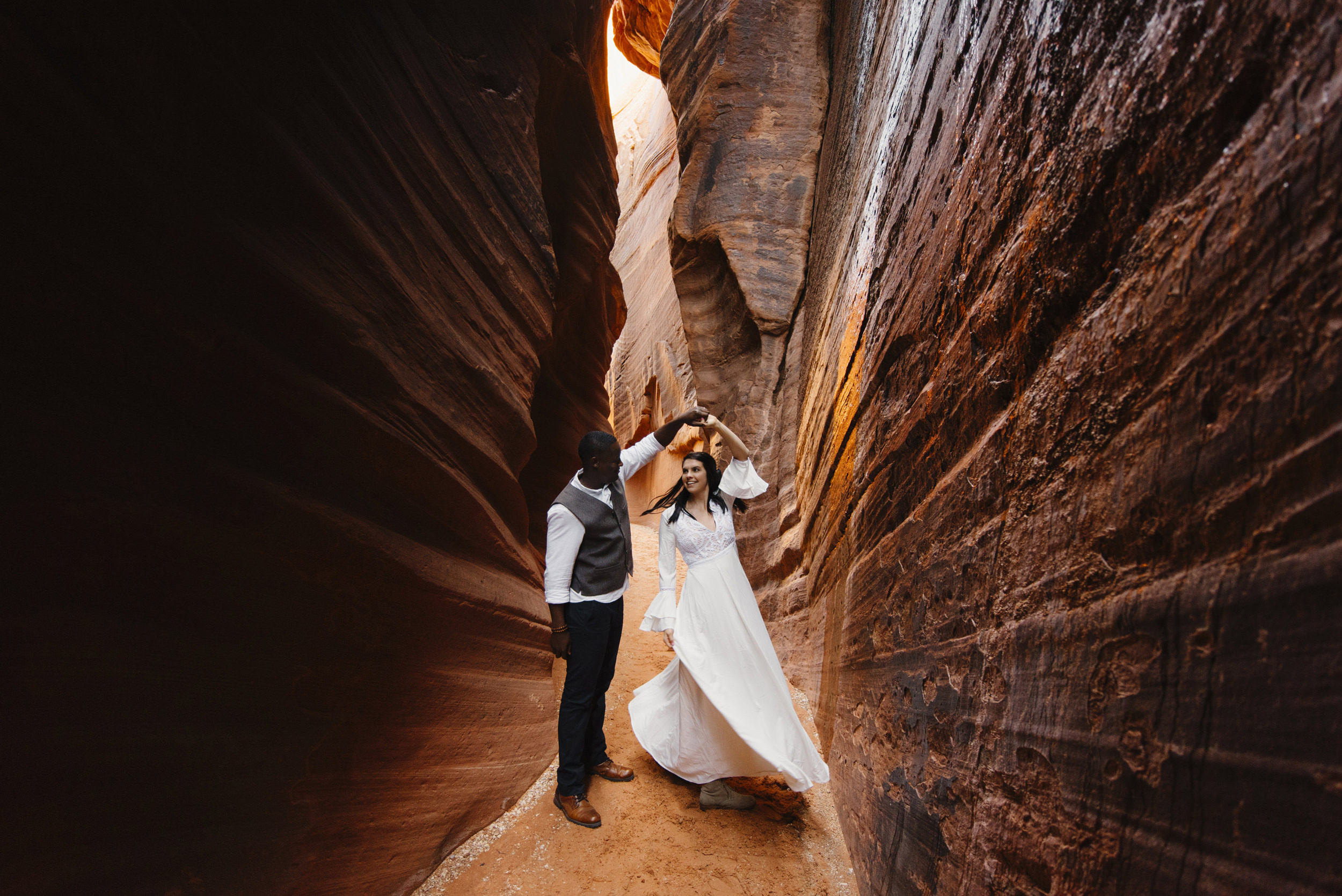 A man and woman dance in a slot canyon during their Antelope Canyon couples adventure photography session with Utah Destination Elopement Photographer Colby and Jess