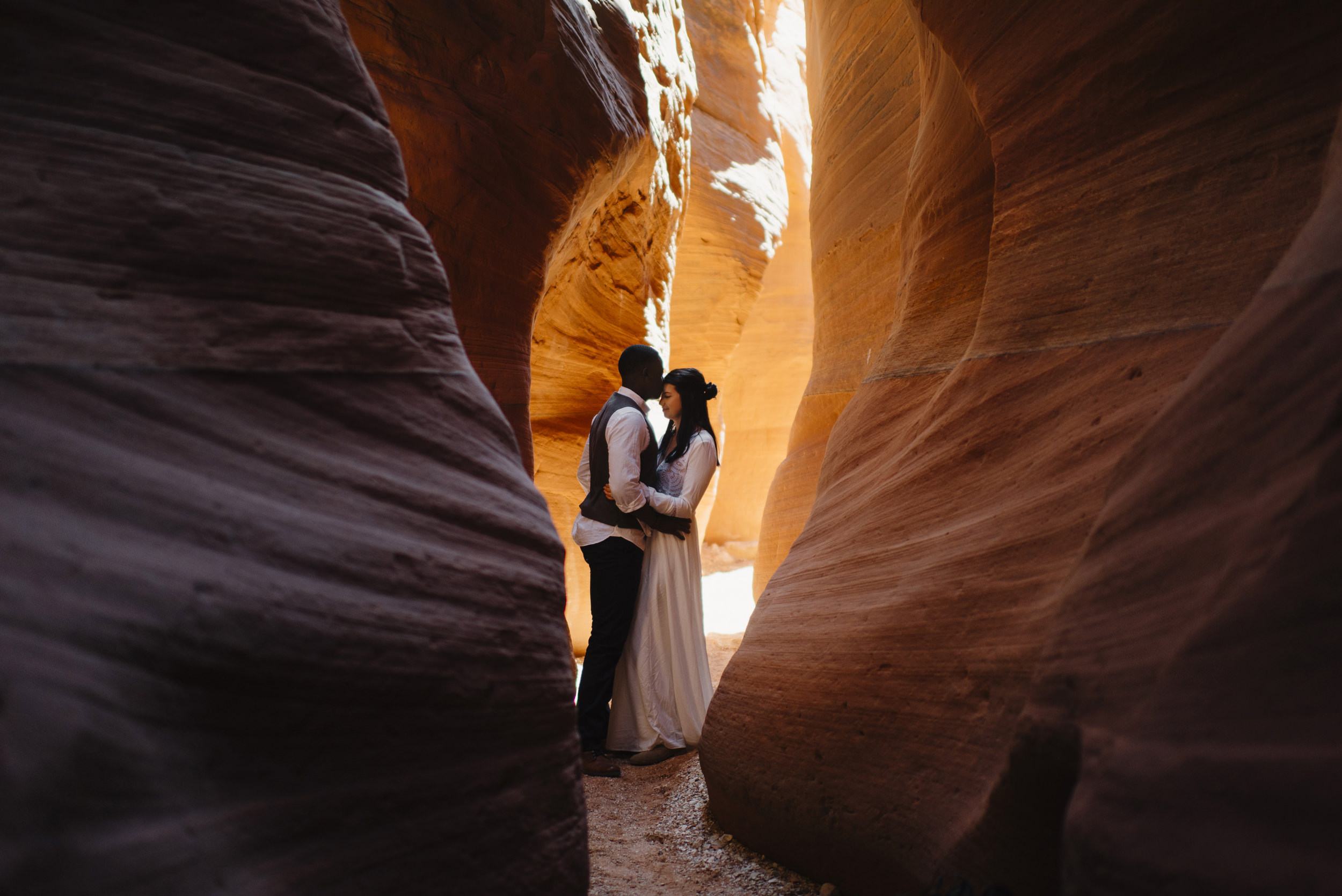 A couple embraces in a slot canyon during their Antelope Canyon Adventure Engagement Photography Session by Utah Destination Elopement Photographer Colby and Jess