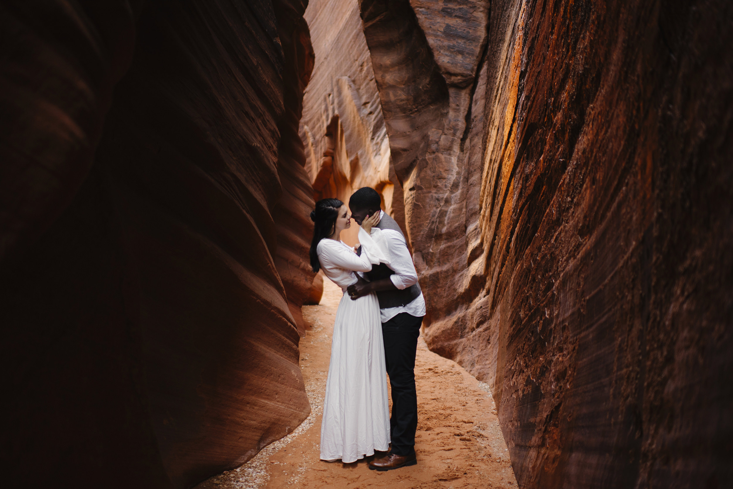 A couple embraces during their slot canyon adventure engagement photography session by Utah Destination Elopement Photographer Colby and Jess
