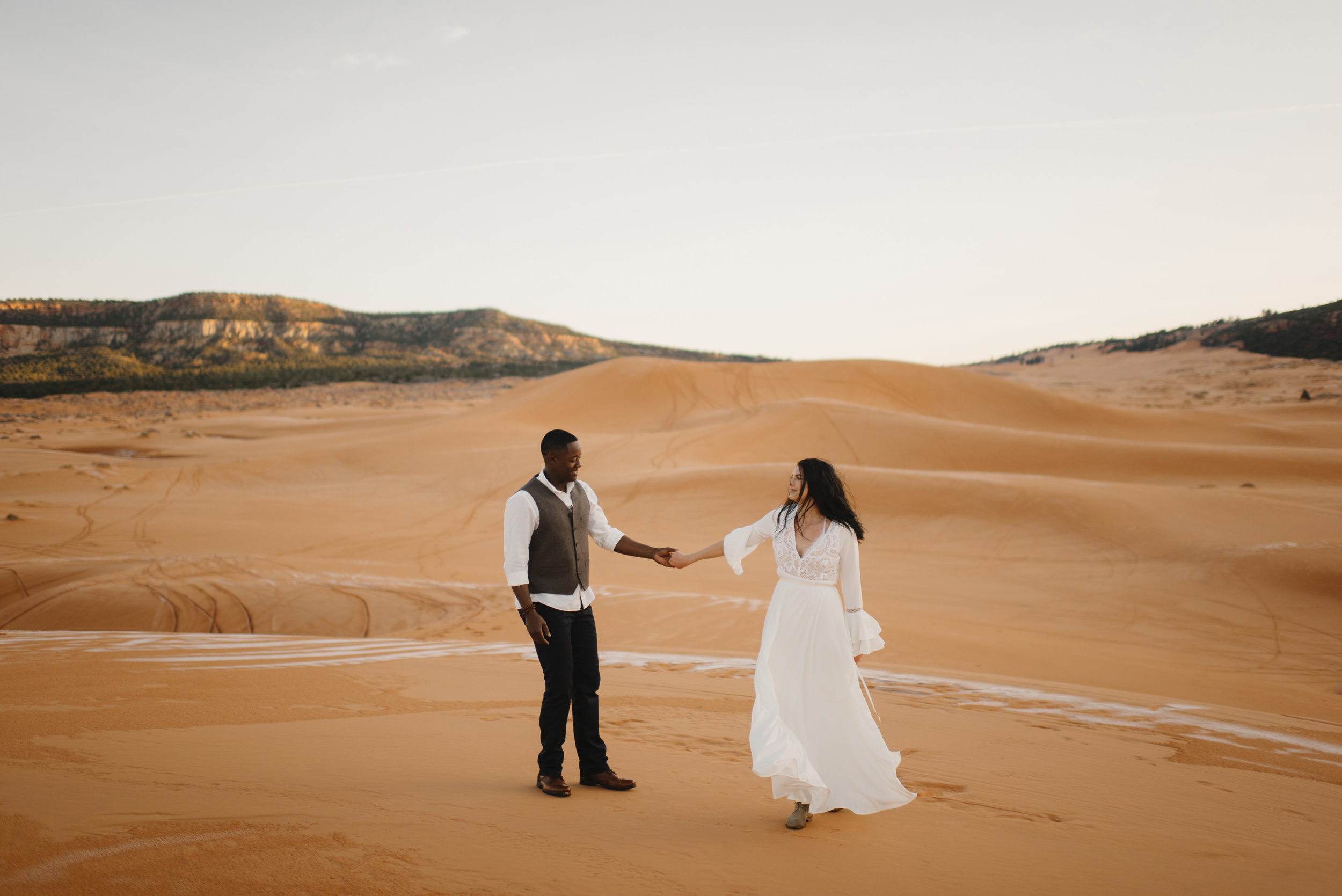 A man and woman dance during their Coral Pink Sand Dunes Adventure Couples Photography Session by Utah Destination Elopement Photographer Colby and Jess